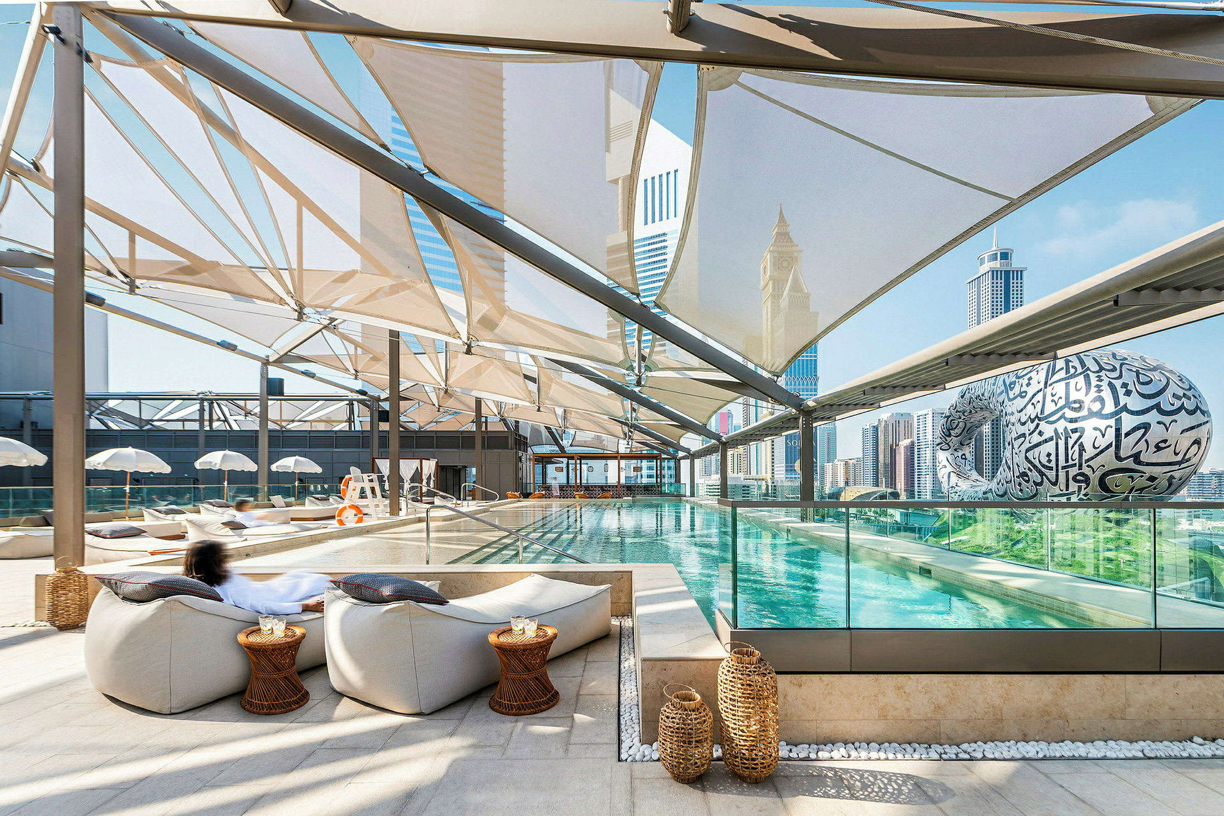 En moderne udendørs pool med siddepladser og udsigt over byens skyline. (AI-genereret tekst)