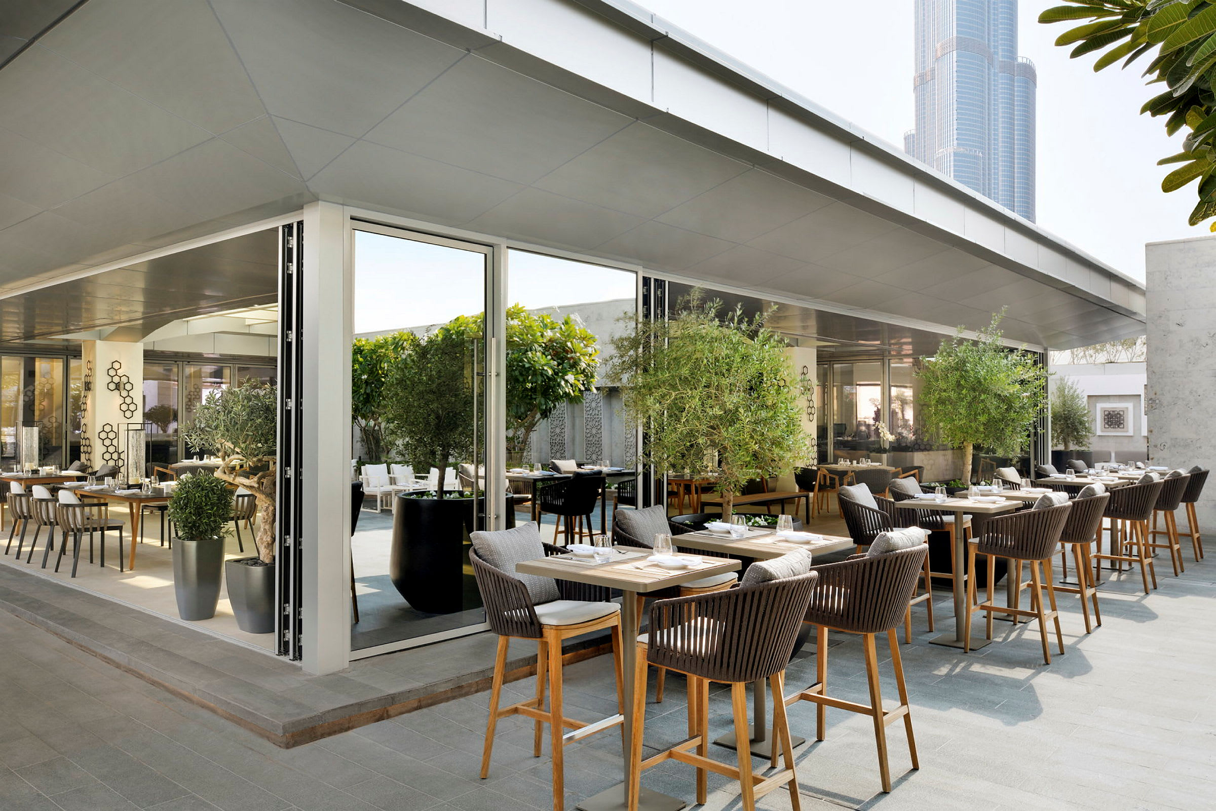 En moderne restaurant med udendørs siddepladser dekoreret med grønne planter og moderne møbler. (AI-genereret tekst)