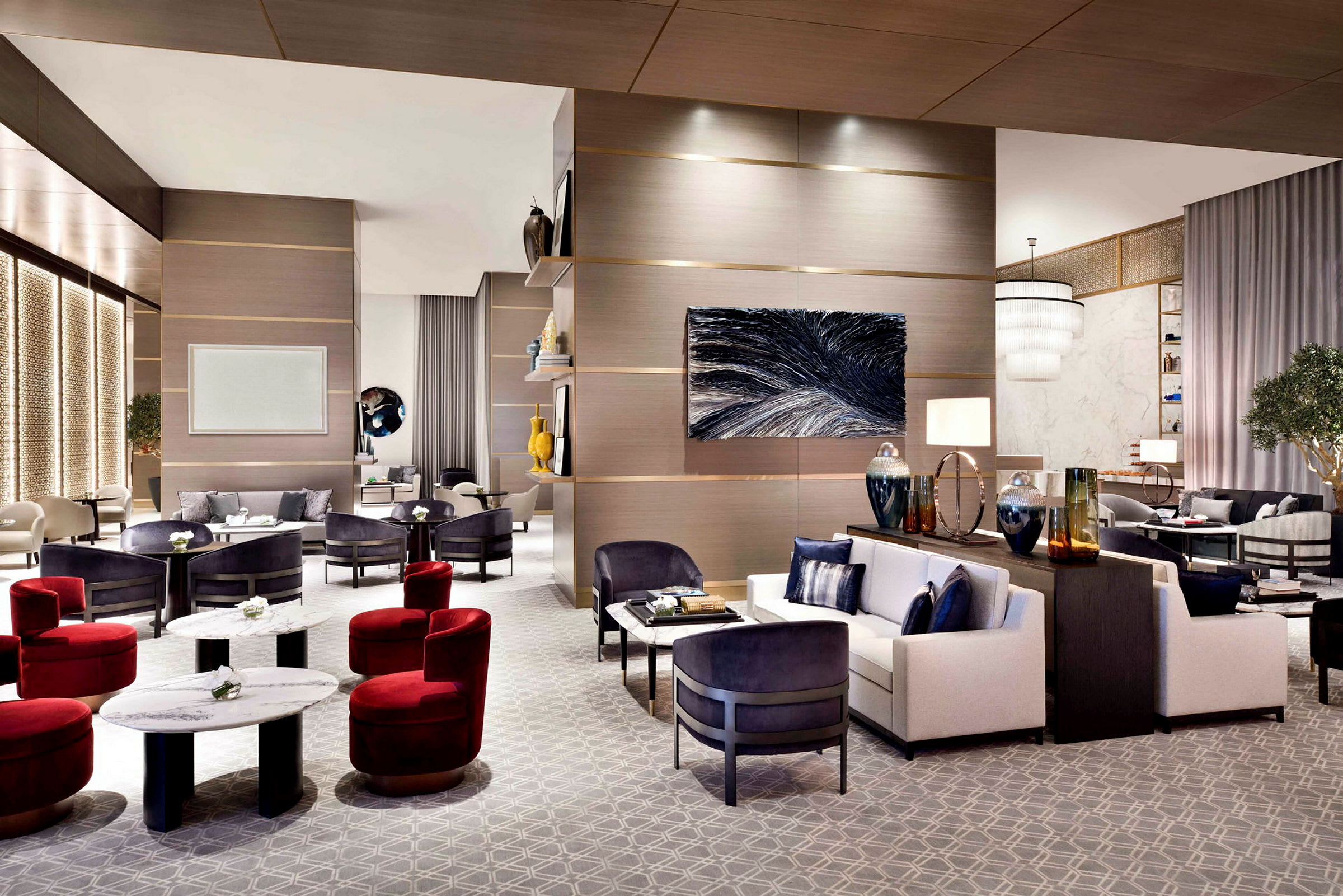 En elegant hotellobby med moderne møbler, herunder sofaer, lænestole og sofaborde. Rummet har interiørdetaljer som vægkunst, belysning og dekorative genstande. (AI-genereret tekst)
