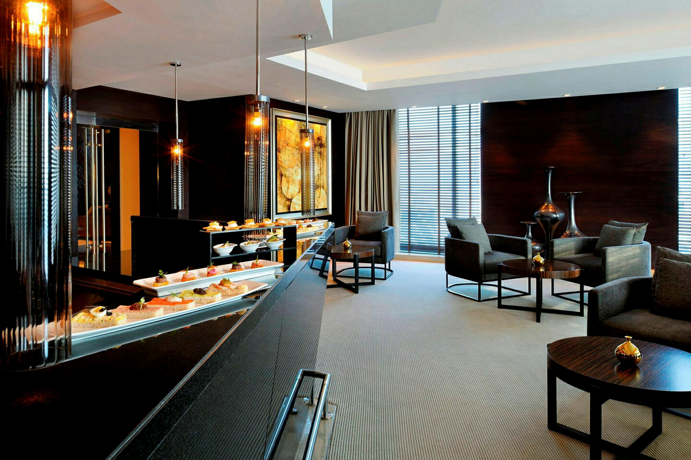 Et elegant hotelloungeområde med en buffet foran og siddegrupper med lænestole og små borde i baggrunden. (AI-genereret tekst)