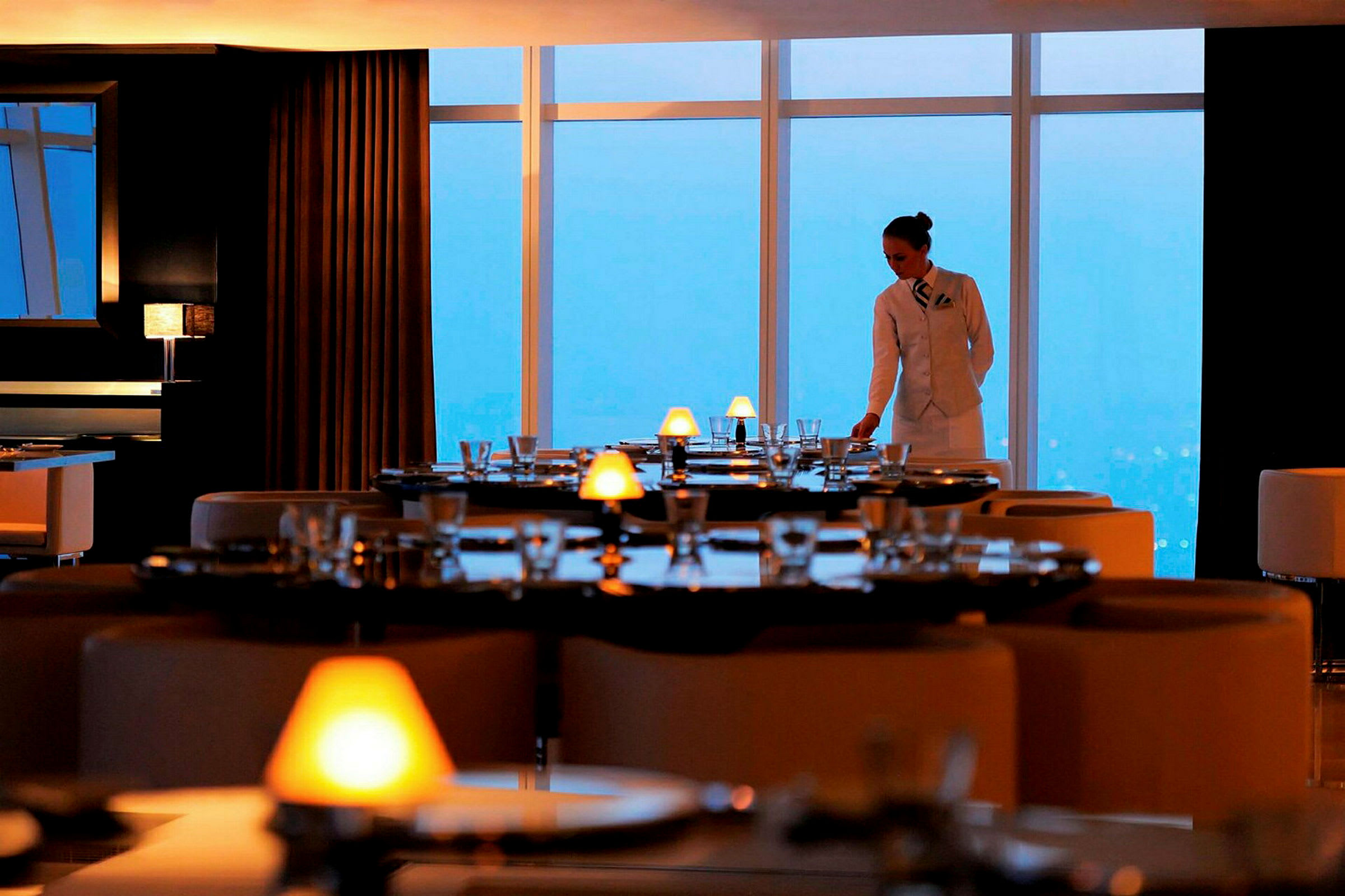En restaurant med elegant dækkede borde og store vinduer med udsigt. (AI-genereret tekst)