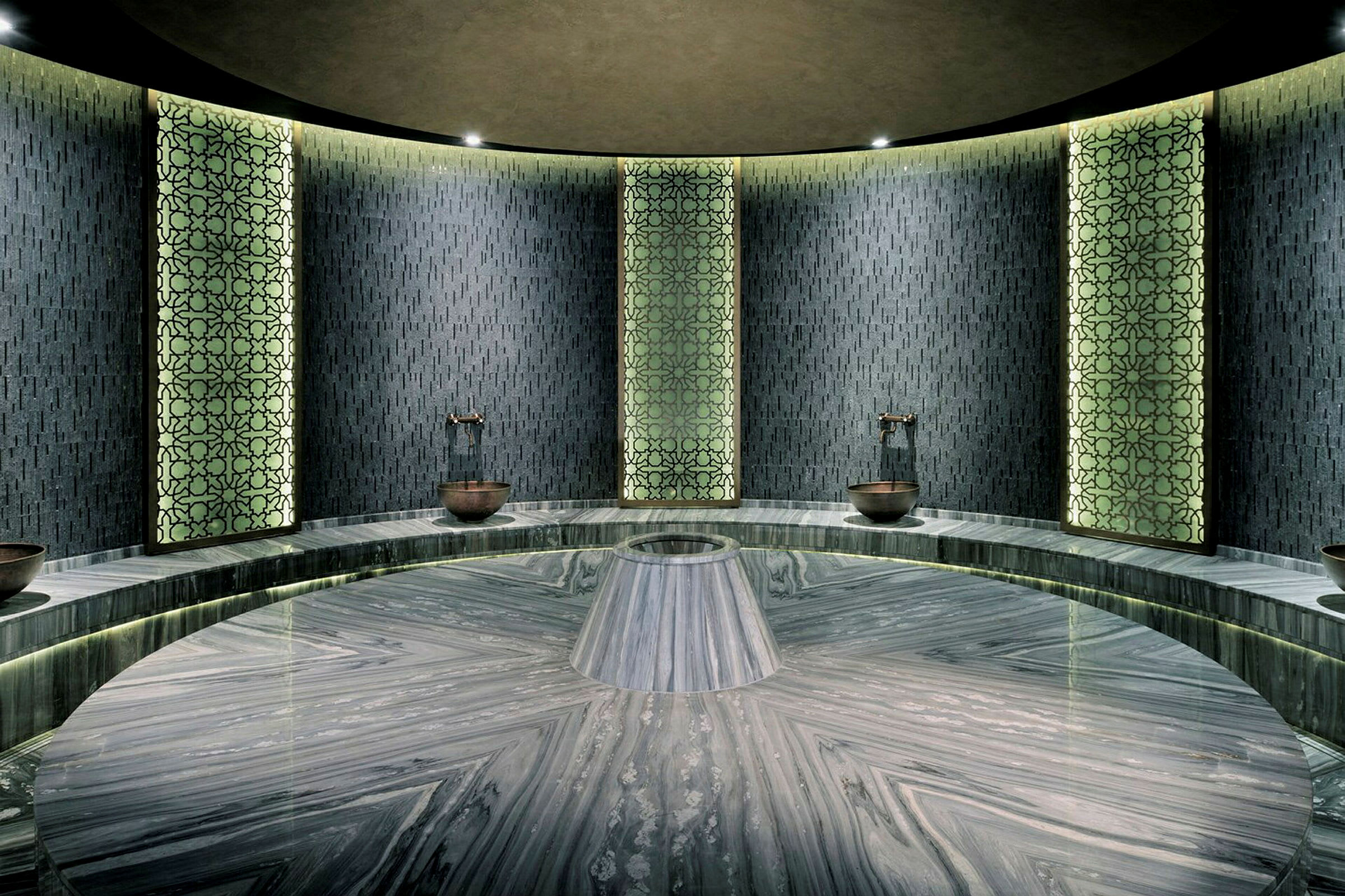 Et moderne designet hamam med mønstrede vægpaneler og en rund marmorplatform i midten. (AI-genereret tekst)