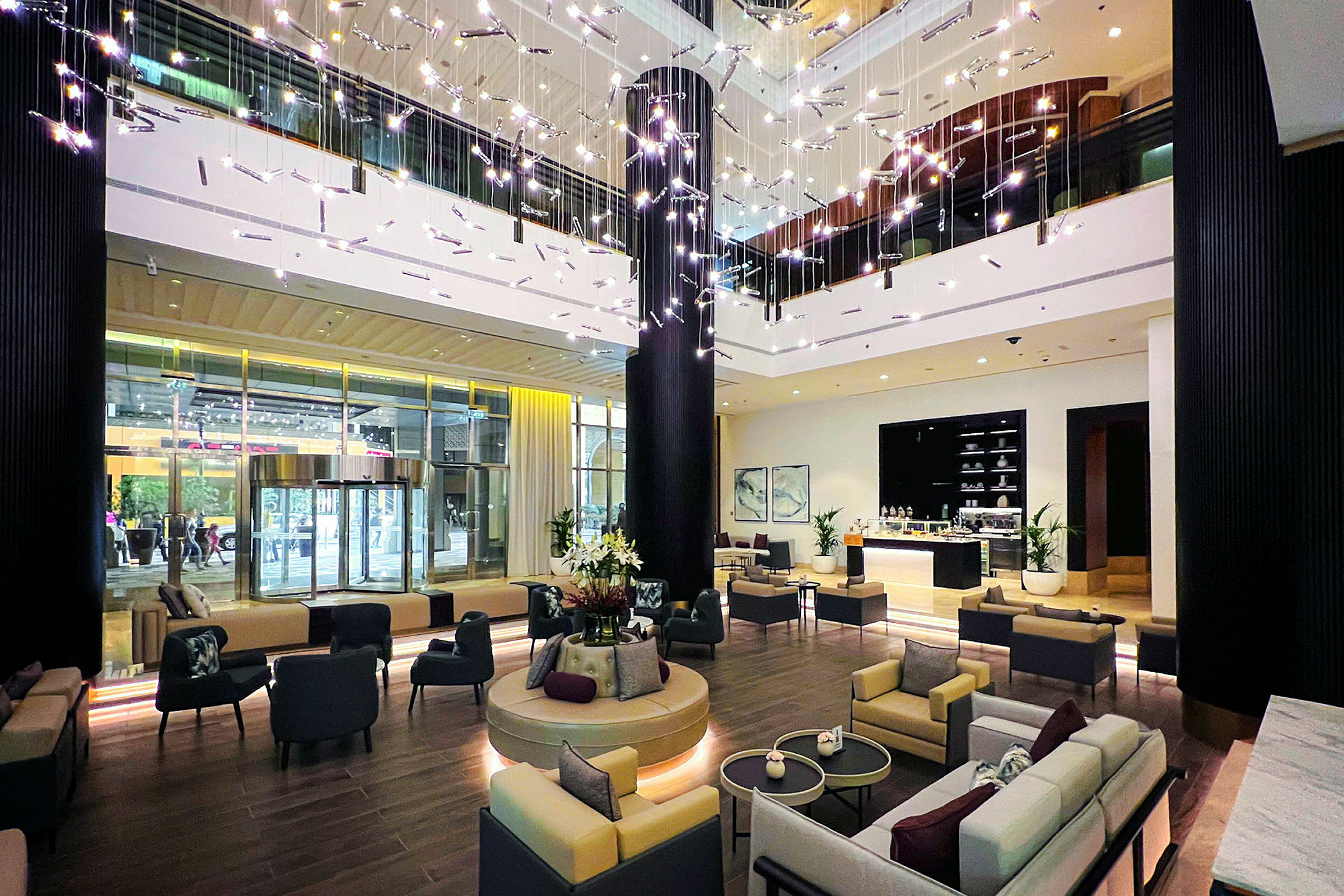 Interiørbillede af en moderne hotellobby med siddegrupper, dekorative lysinstallationer og en reception. (AI-genereret tekst)