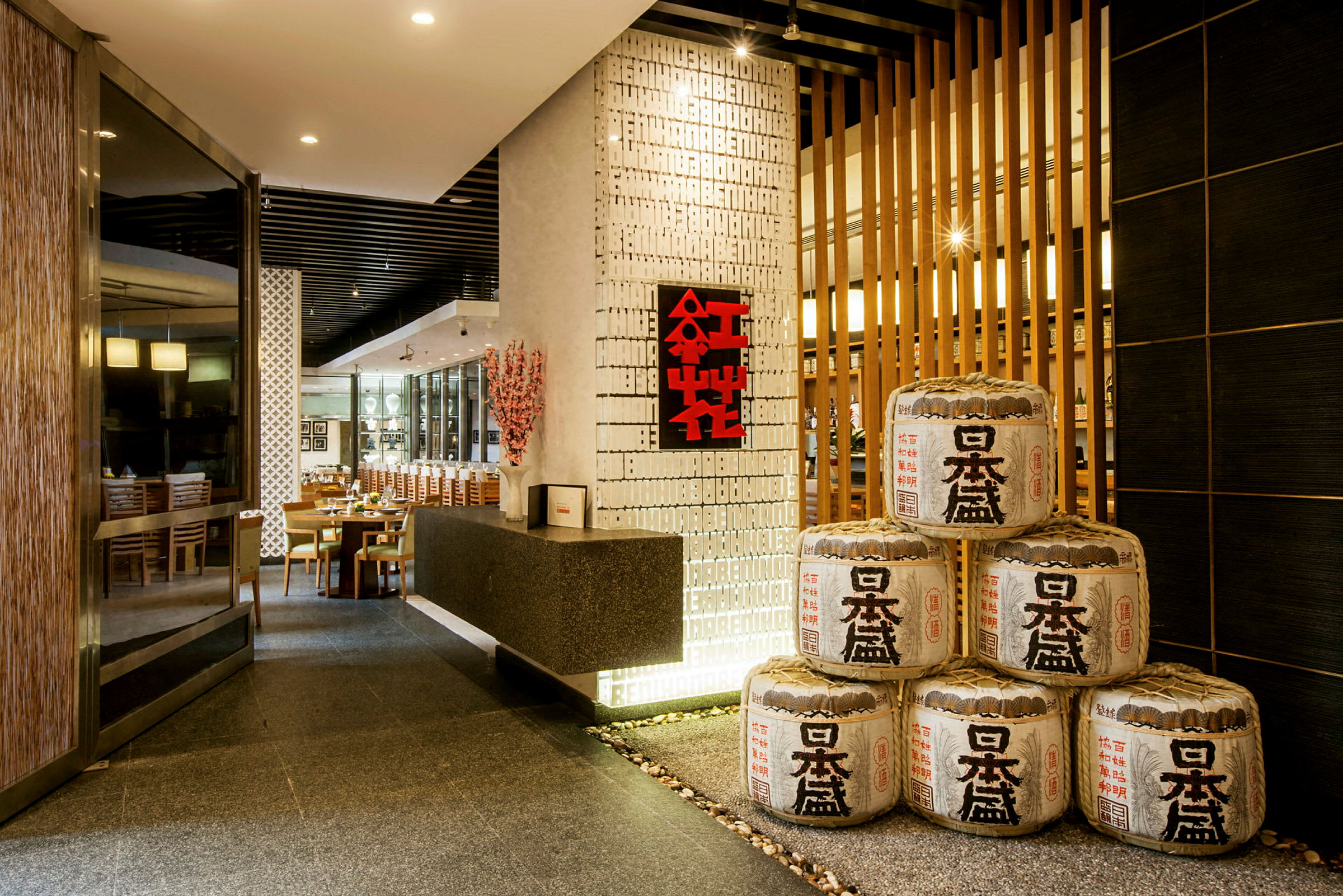 Indgangen til en elegant restaurant med japansk dekoration og ris-fad-lignende ornamenter stablet i hjørnet. (AI-genereret tekst)