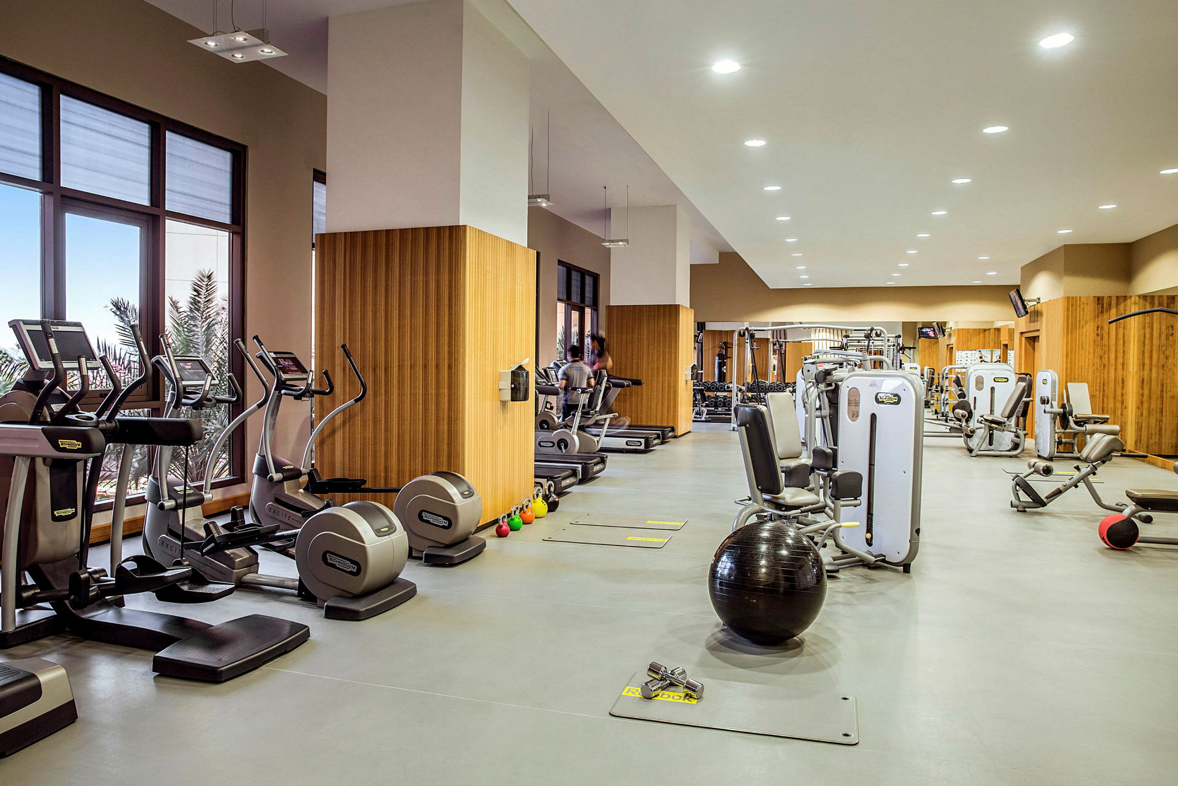 Fitnesscenter med forskellige træningsmaskiner og udstyr. (AI-genereret tekst)