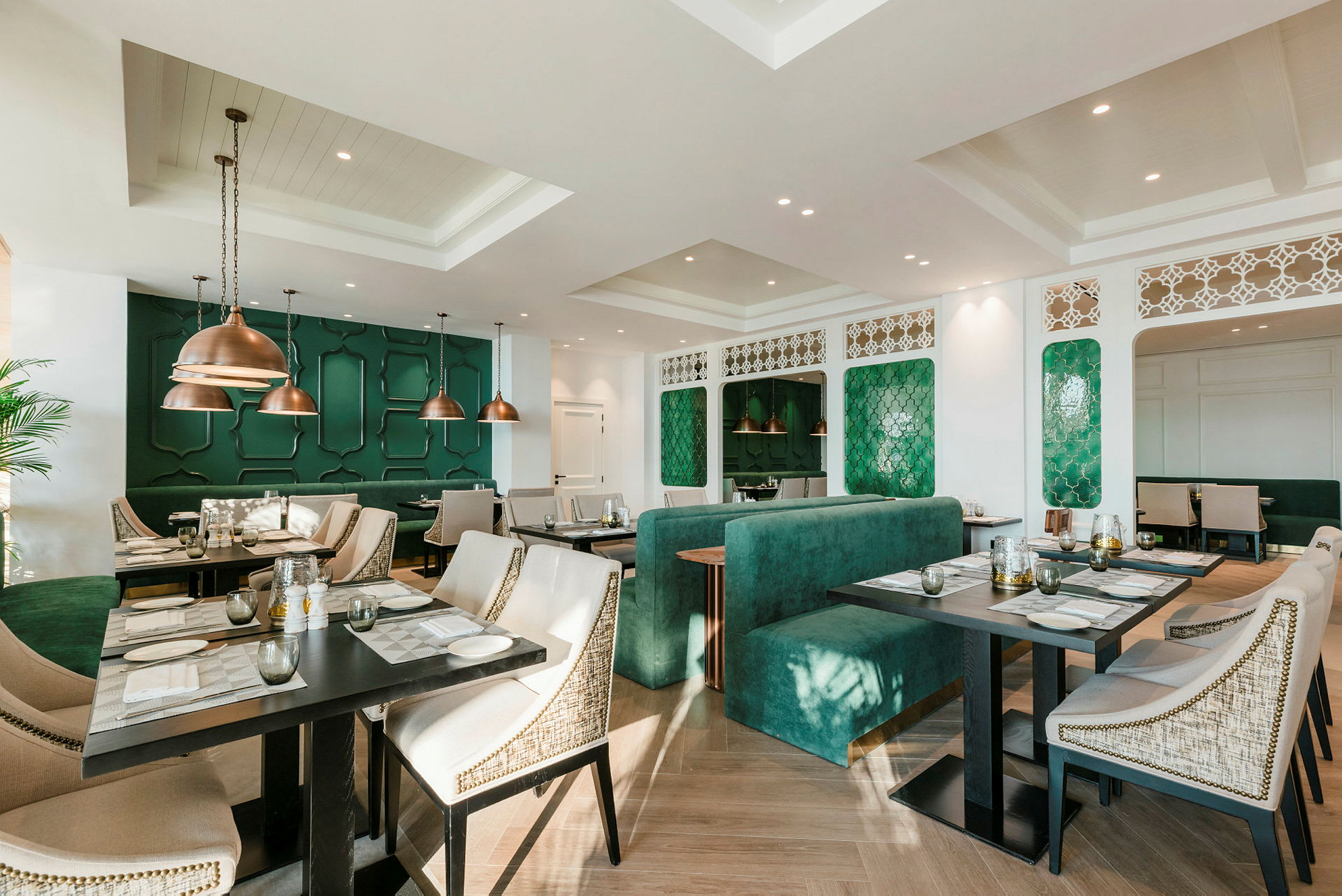 Billede af en elegant restaurant med grønne dekorative vægpaneler og moderne møbler. (AI-genereret tekst)