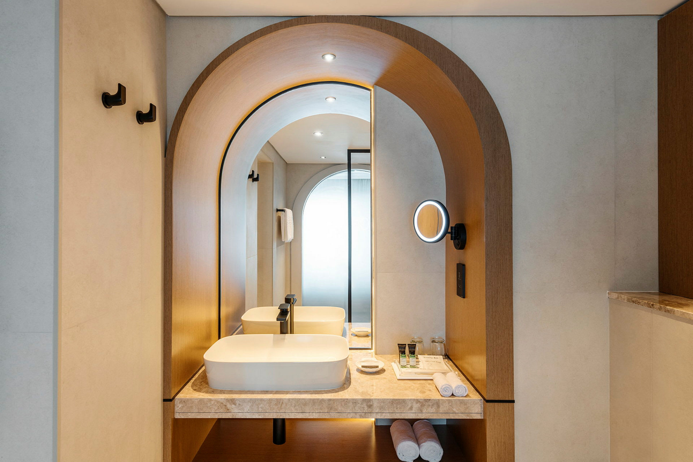 Moderne hotelbadeværelse med elegant indretning, håndvask og belyst spejl. (AI-genereret tekst)