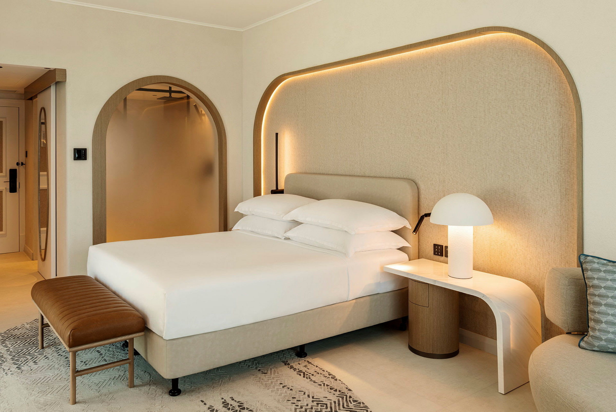 Billede af et moderne hotelværelse med en opredt seng, natbord med lampe og en sidemøbel. (AI-genereret tekst)