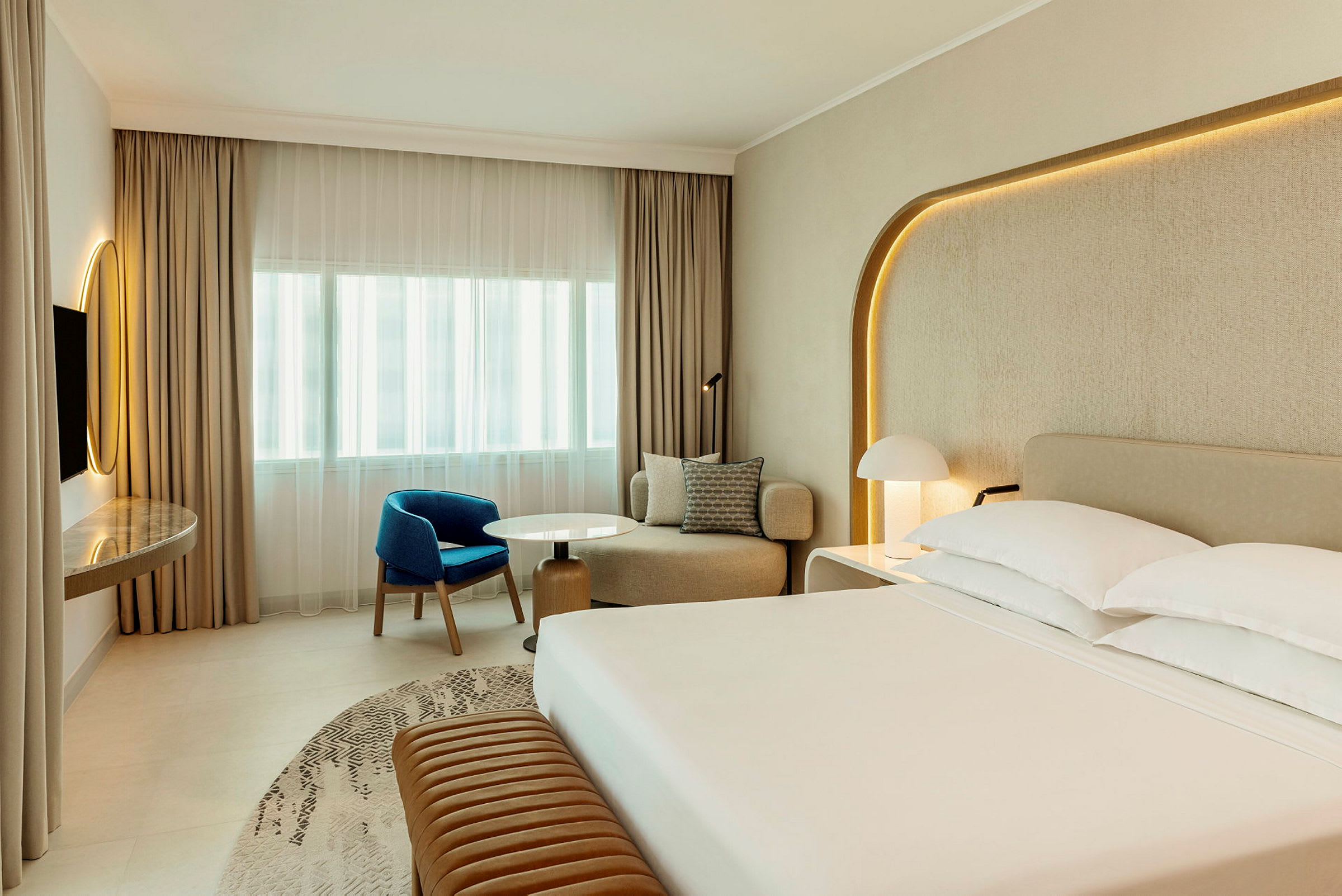 Et moderne hotelværelse med en stor seng, siddeområde og skrivebord. (AI-genereret tekst)