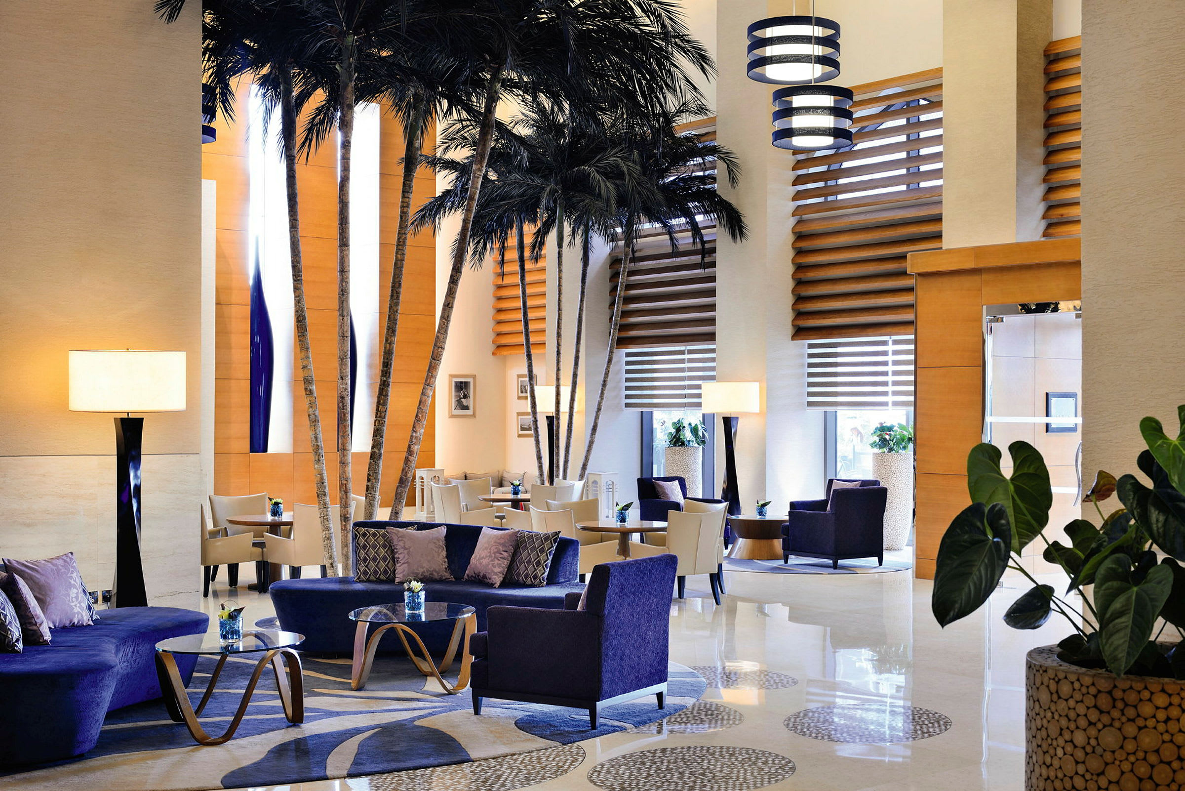 Luksuriøst indrettet hotellobby med komfortable siddemøbler og dekorative palmer. (AI-genereret tekst)
