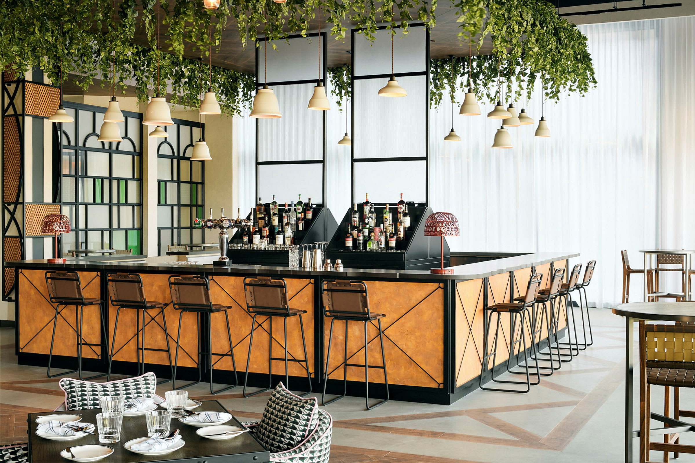 En elegant bar med barstole, flasker og grønne hængende planter. (AI-genereret tekst)