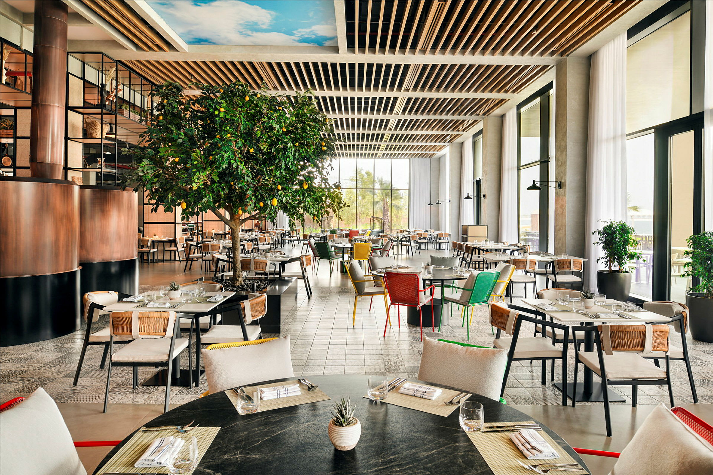 En lys og rummelig restaurant med moderne møbler og et stort citrontræ. (AI-genereret tekst)
