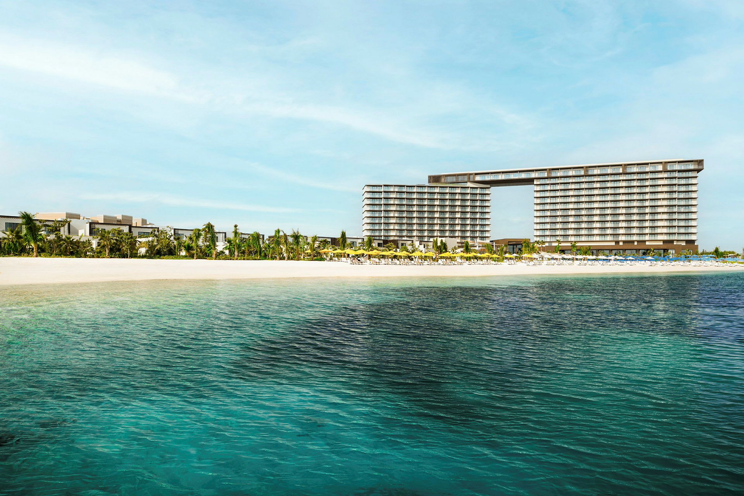 Udsigt over et hotel nær en sandstrand med klart vand. (AI-genereret tekst)