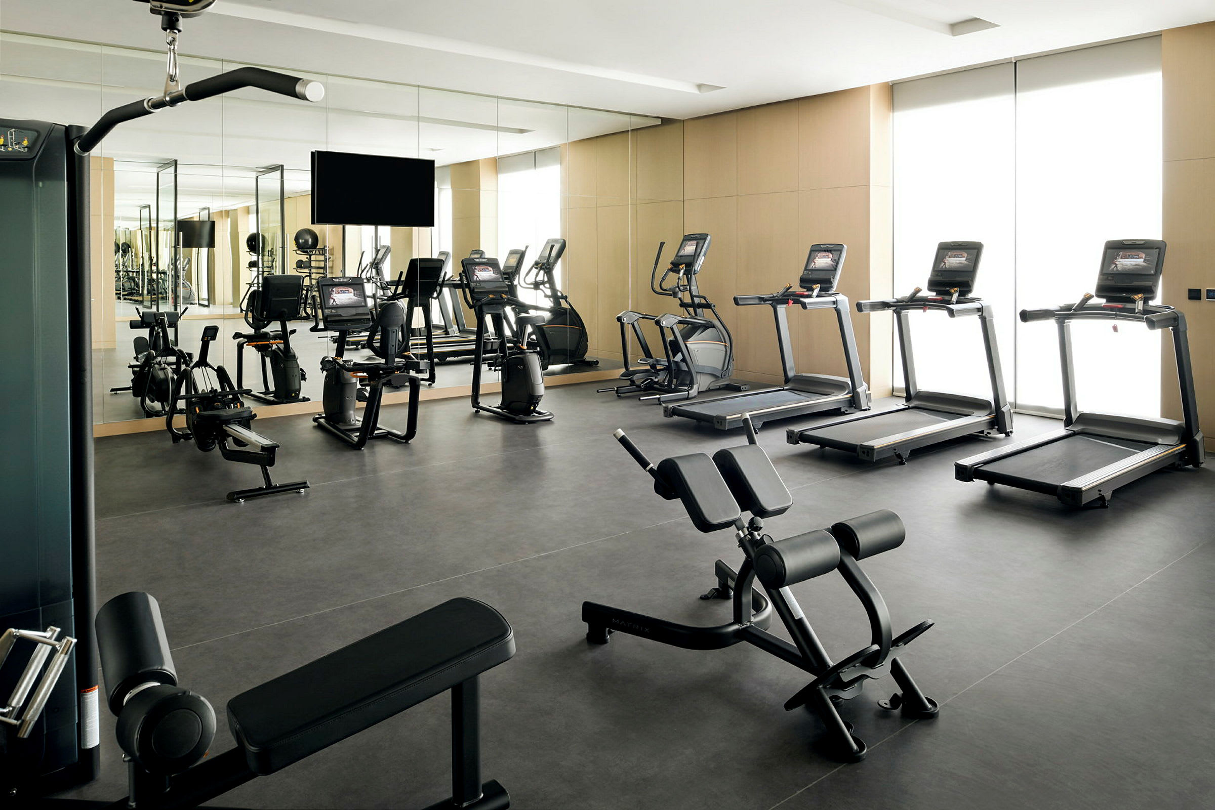 Et fitnesscenter med forskellige træningsmaskiner og spejle på væggene. (AI-genereret tekst)