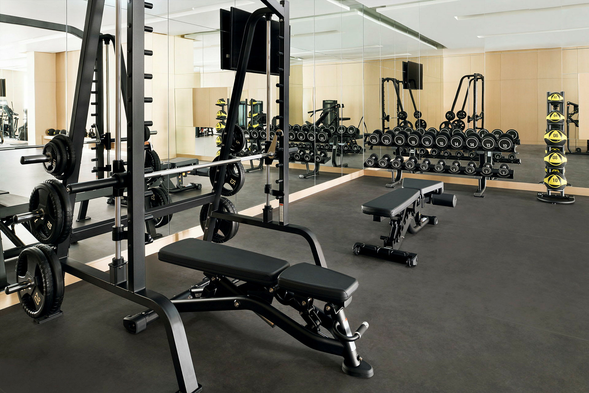 Et fitnesscenter med styrketræningsudstyr, herunder bænke, håndvægte og vægte. (AI-genereret tekst)