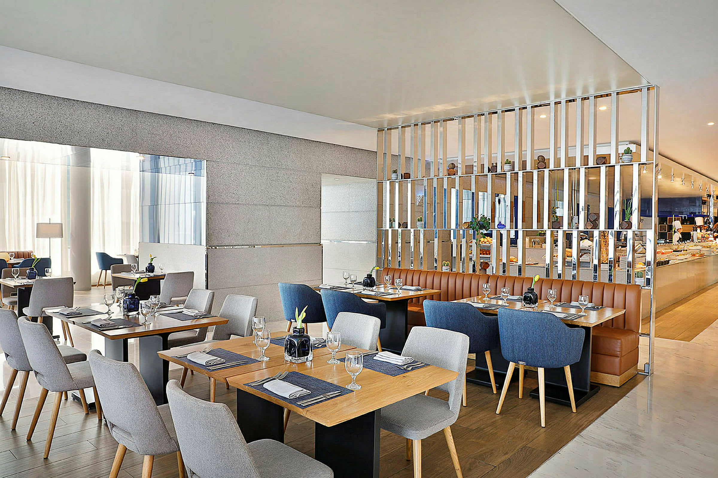 Billede af en moderne restaurant med flere opdækkede borde og stole i forskellige farver. Varm og stilfuld indretning. (AI-genereret tekst)