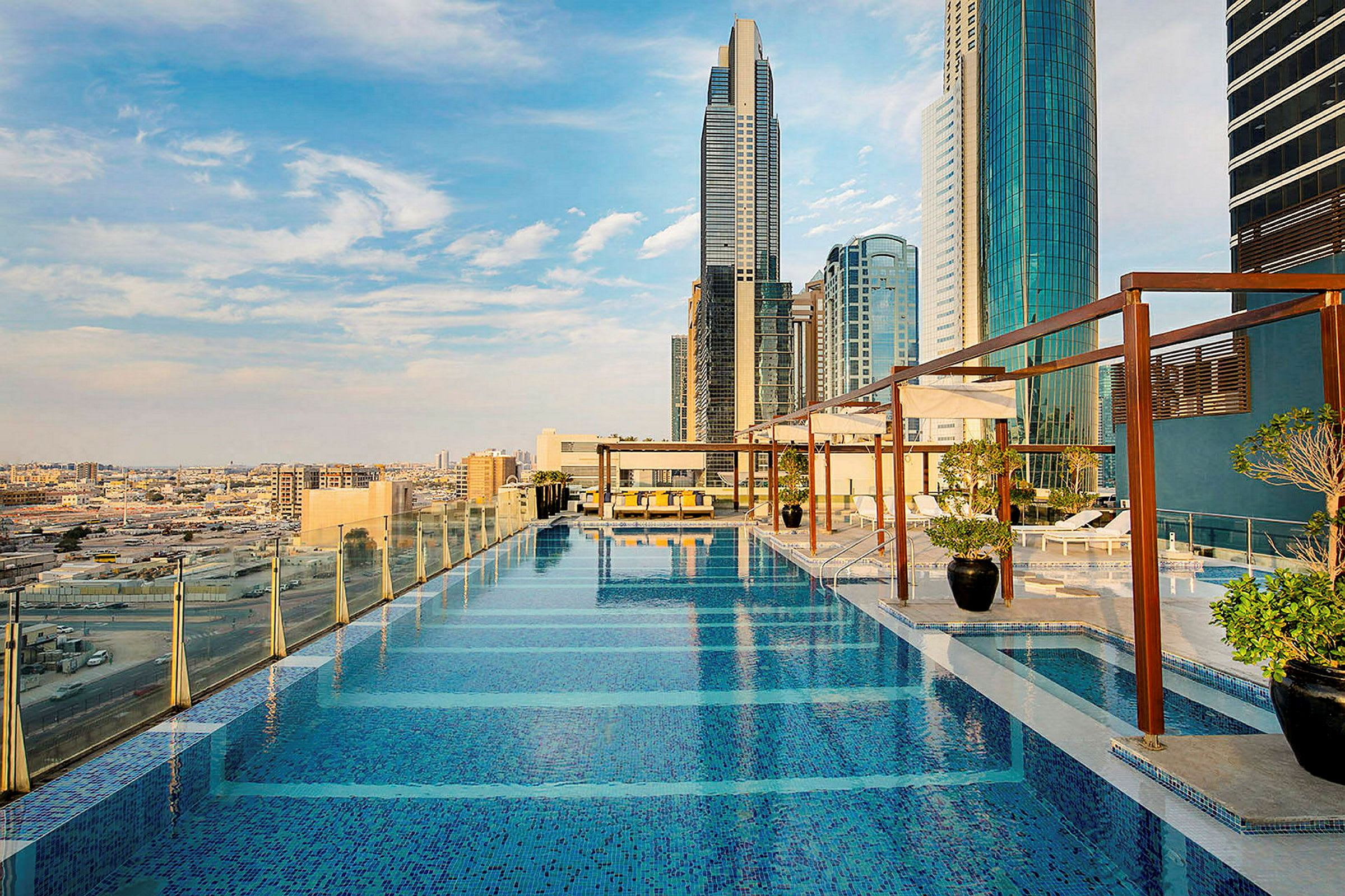 Foto af en infinitypool på en tagterrasse med moderne byskyskrabere i baggrunden. (AI-genereret tekst)