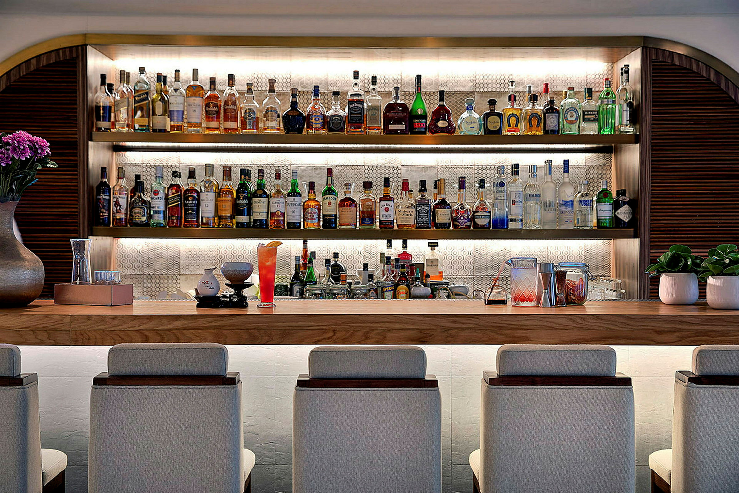 En velassorteret bardisk med siddepladser, spiritusflasker og dekorationer. (AI-genereret tekst)