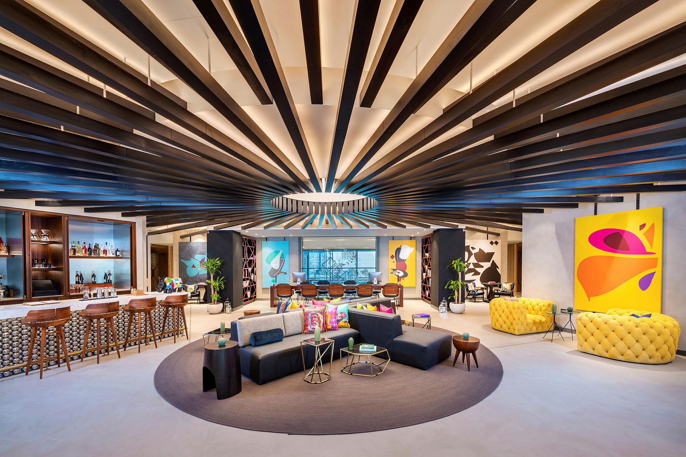 Moderne og farverige møbler i en rummelig lounge med et designet loft og kunst på væggene. (AI-genereret tekst)