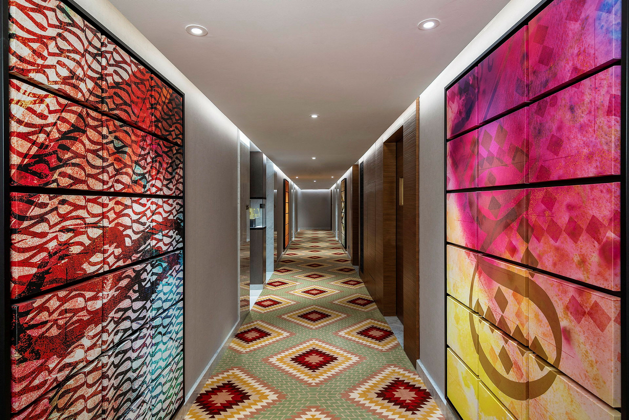Hotelkorridor med farverig kunst på væggene og et geometrisk mønstret gulv. (AI-genereret tekst)