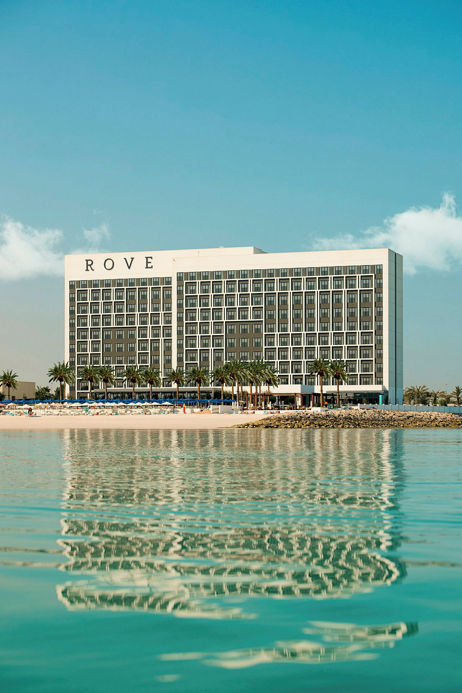 Hotellet Rove ved stranden med palmer og vand. (AI-genereret tekst)