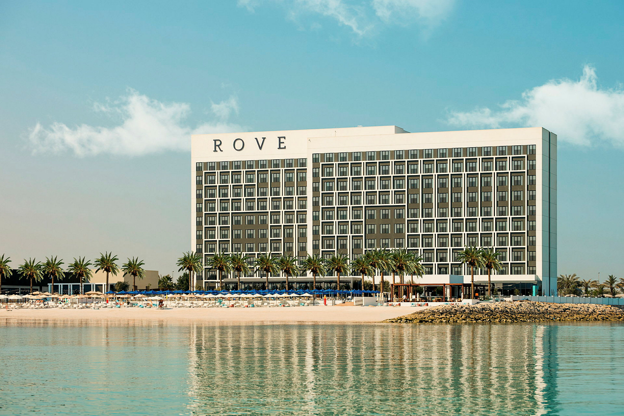 Et hotel ved en strand med palmer. (AI-genereret tekst)