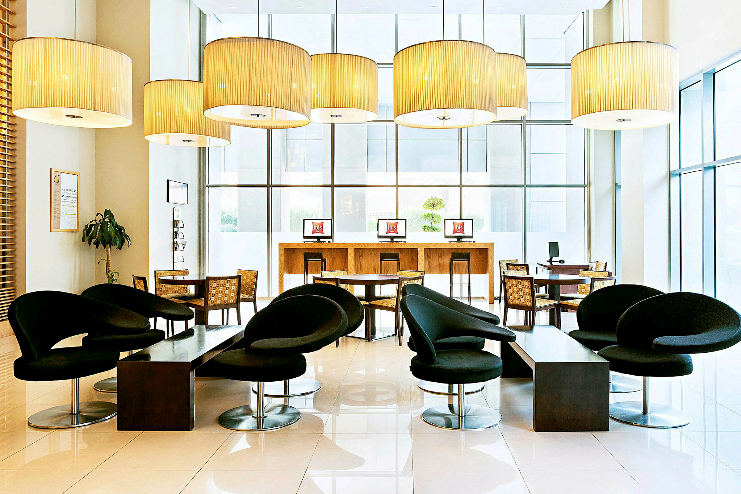 Et moderne møbleret hotellobbyområde med sorte stole, borde og computere. (AI-genereret tekst)