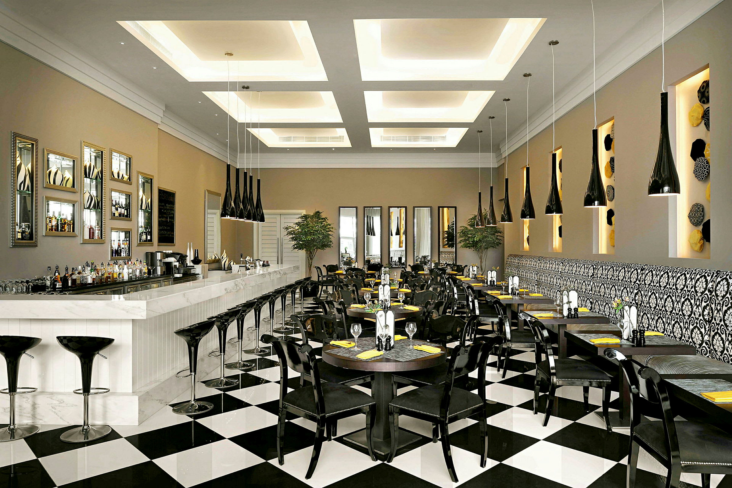 En elegant restaurant eller café med en lang hvid bardisk, sorte stole, bordopsætninger og karakteristisk moderne indretning. (AI-genereret tekst)