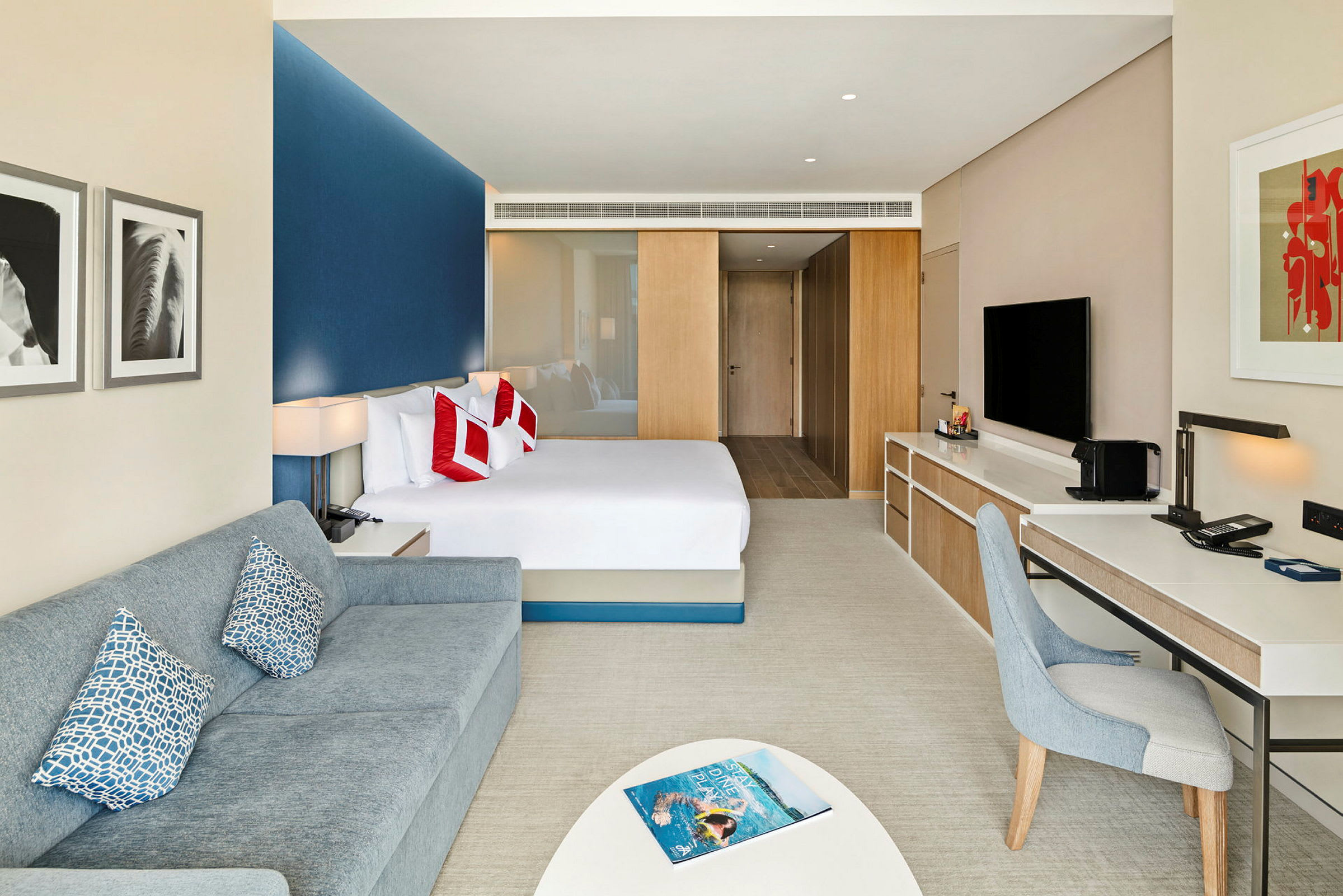 Moderne hotelværelse med seng, sofa og skrivebord. (AI-genereret tekst)