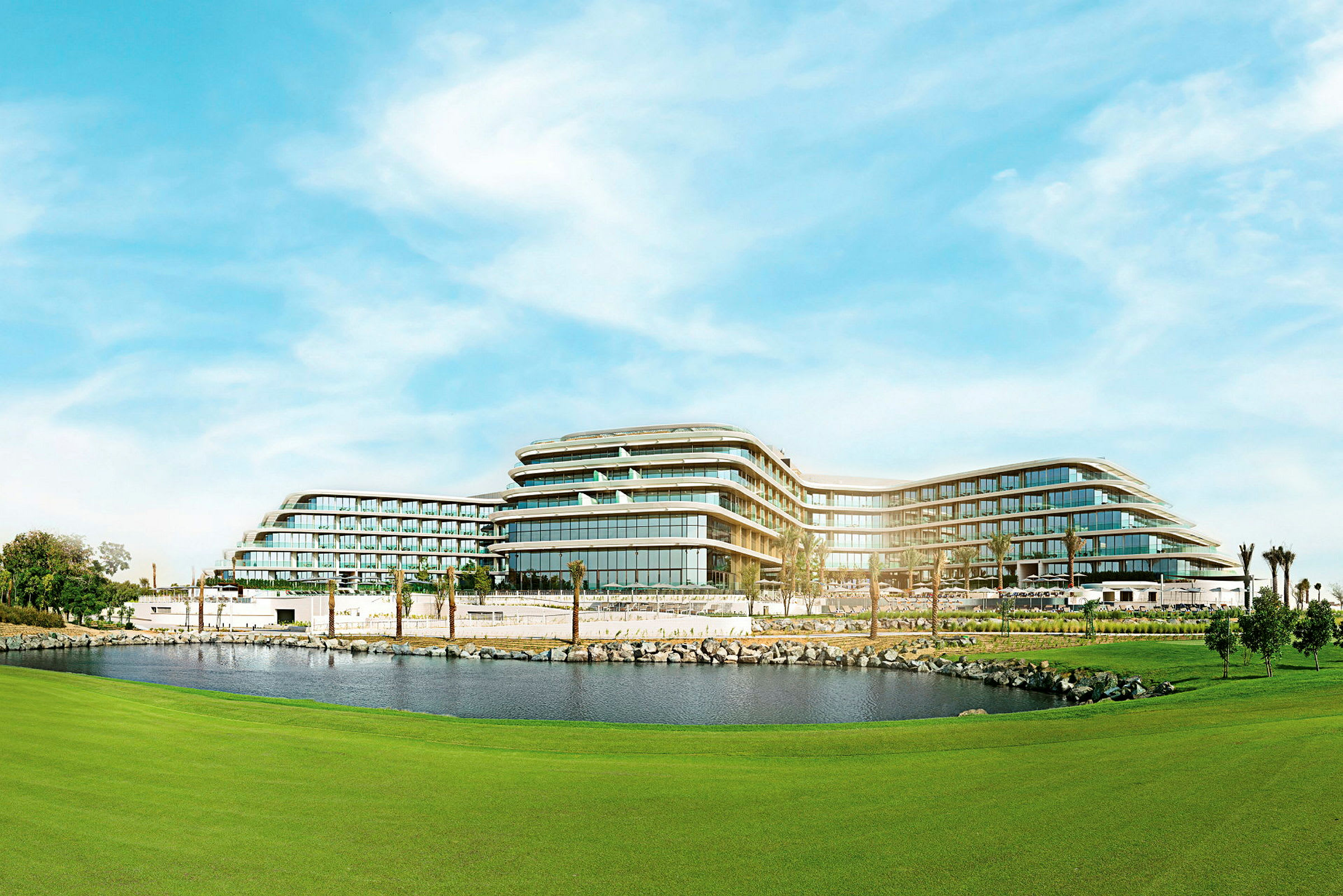 Et moderne hotel med fleretagesbygninger omgivet af grønne områder og en dam. (AI-genereret tekst)
