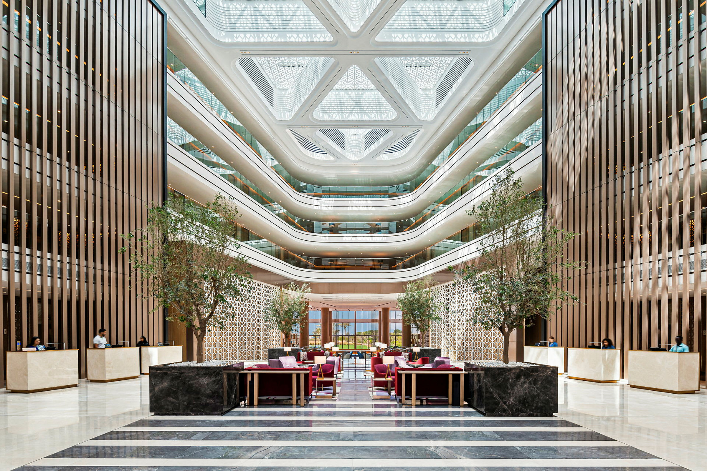 Et moderne hotelatrium med flere etager, store vinduer, dekorative træpaneler og receptioner. (AI-genereret tekst)