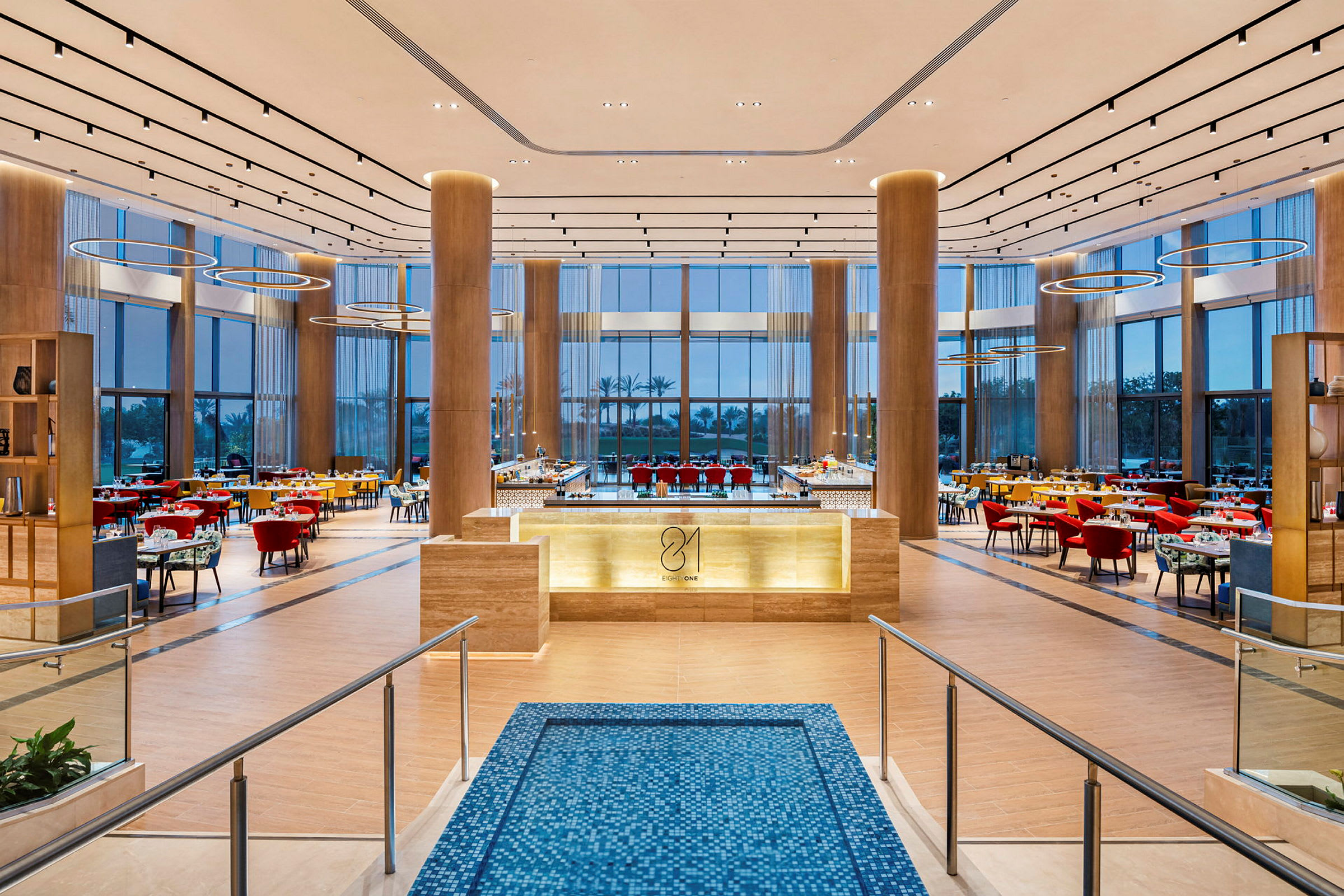 En stor og elegant restaurant med moderne møbler er godt oplyst. Der er borde og stole placeret rundt om i lokalet. (AI-genereret tekst)