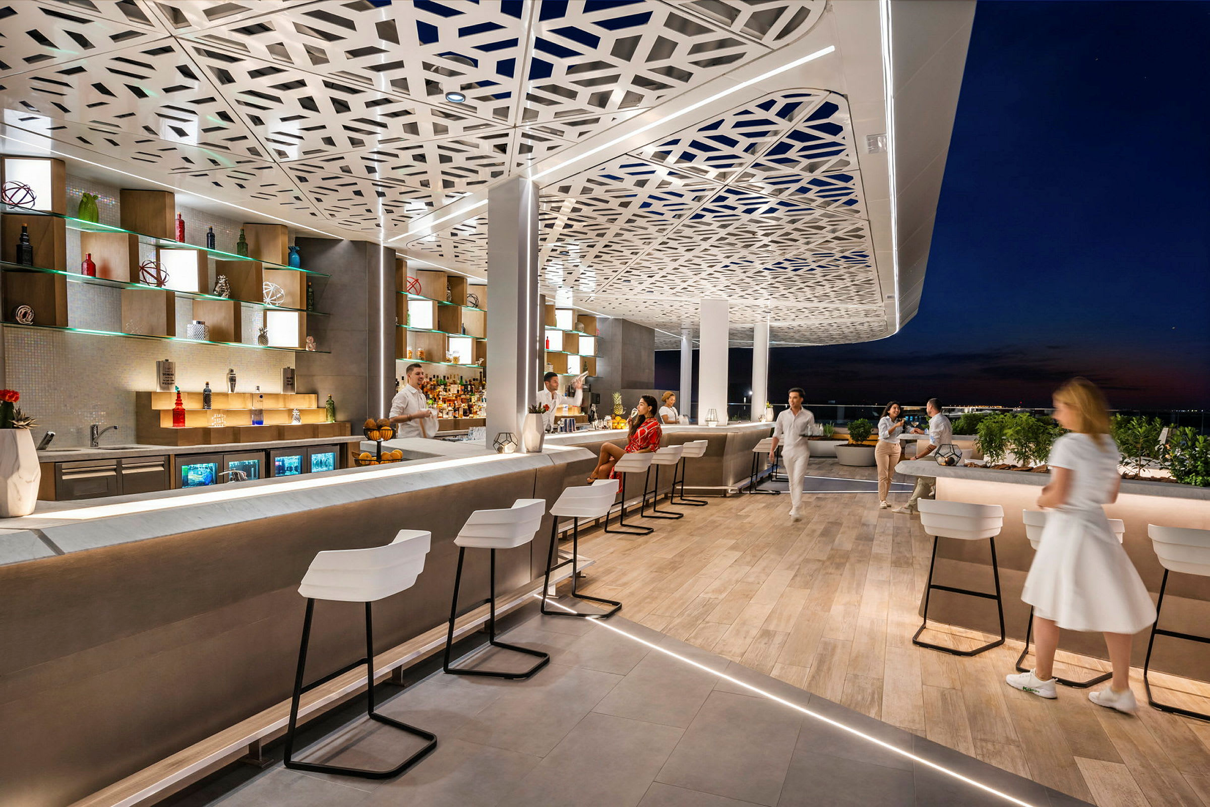 En moderne tagterrasse med elegante barstole, en oplyst bardisk og dekorativt loft. Folk nyder en aftenstemning. (AI-genereret tekst)