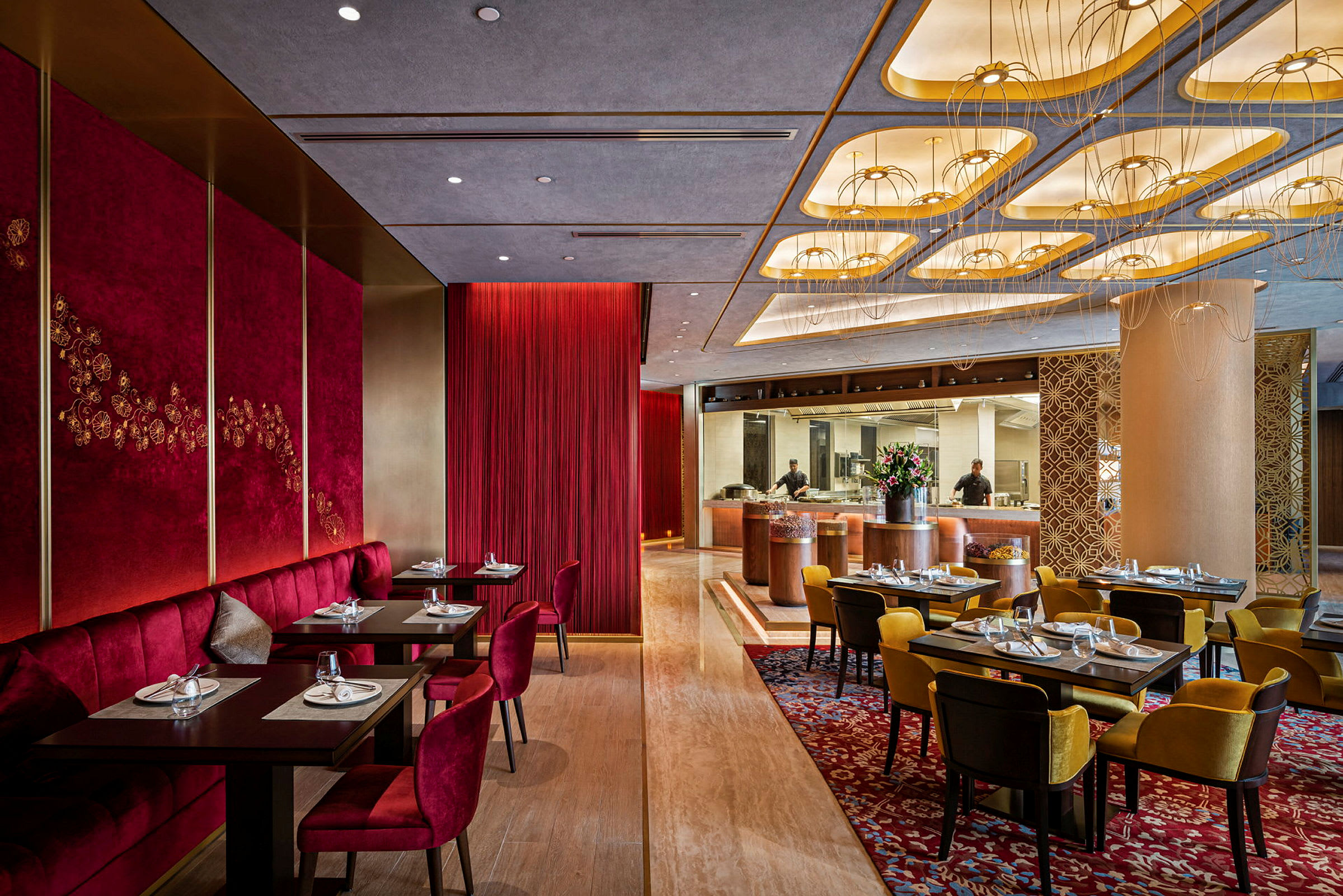 En elegant restaurant med røde og gule siddepladser, smukt dekorerede lofter og et åbent køkken. (AI-genereret tekst)