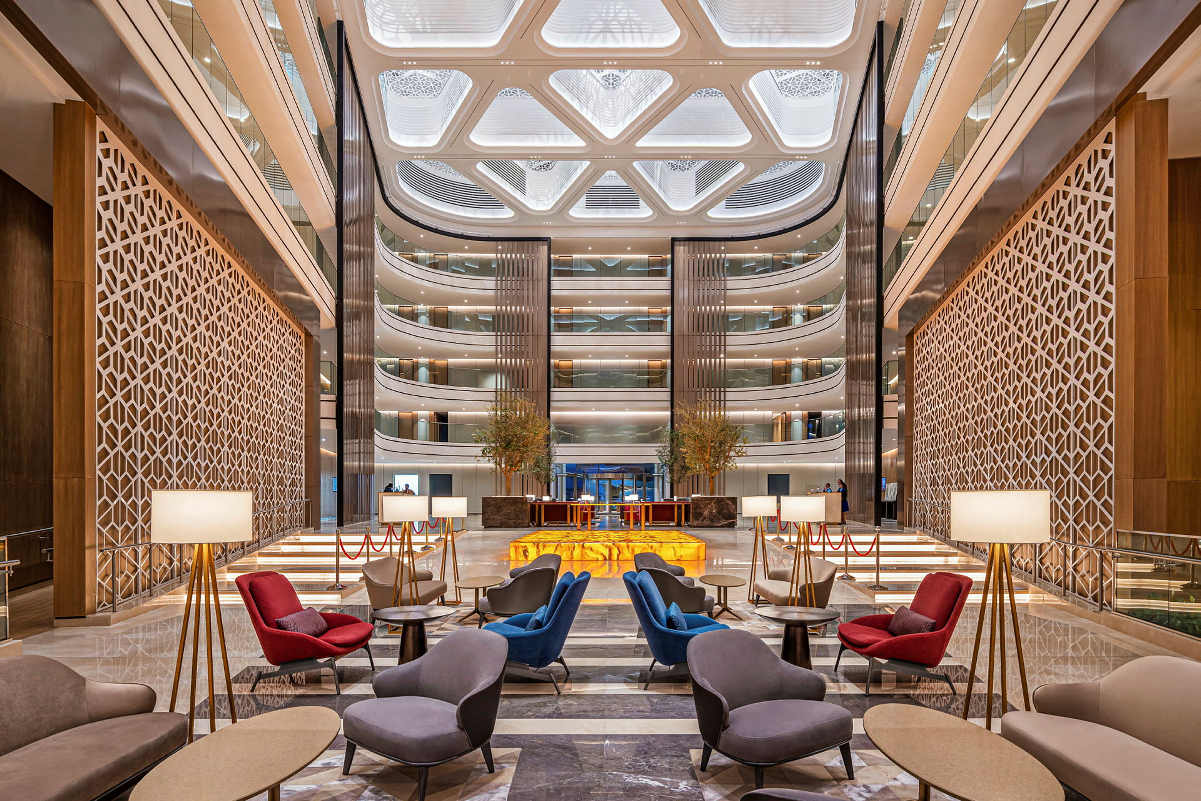 Et elegant hotellobbyområde med moderne siddegrupper, gulvlamper og et imponerende loftdesign. (AI-genereret tekst)