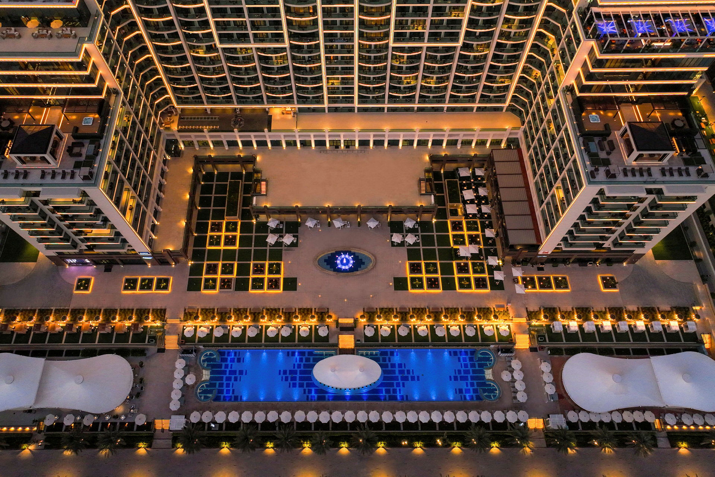Luftfoto af et hotelkompleks med oplyste bygninger og en pool. (AI-genereret tekst)
