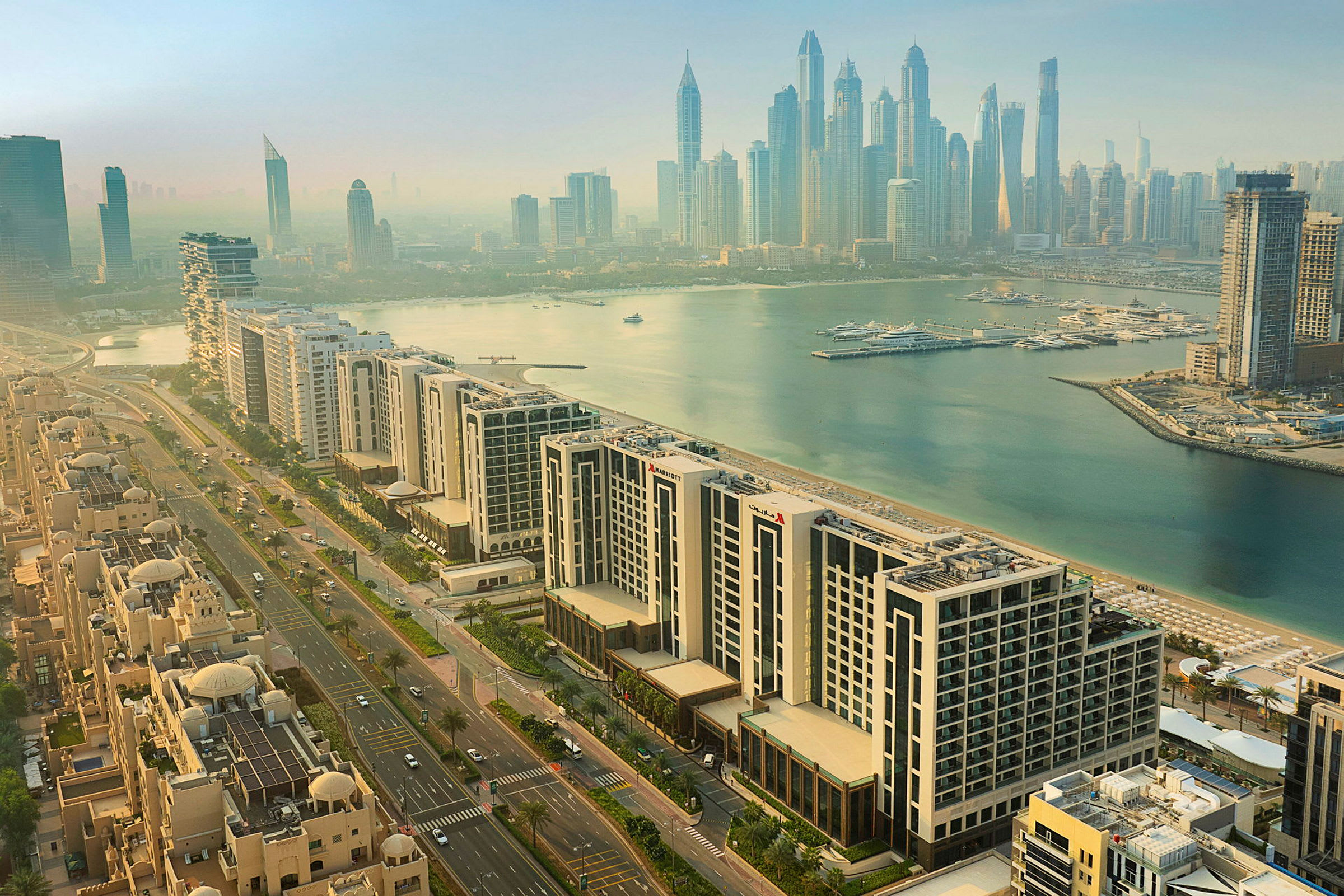 Luftigt udsyn over Dubai Marina med moderne højhuse, boligområder og lystbådehavn ved vandet. (AI-genereret tekst)