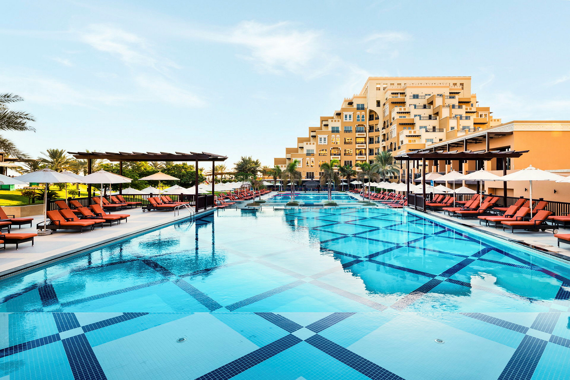 En stor swimmingpool med liggestole og parasoller ved siden af et hotel. (AI-genereret tekst)