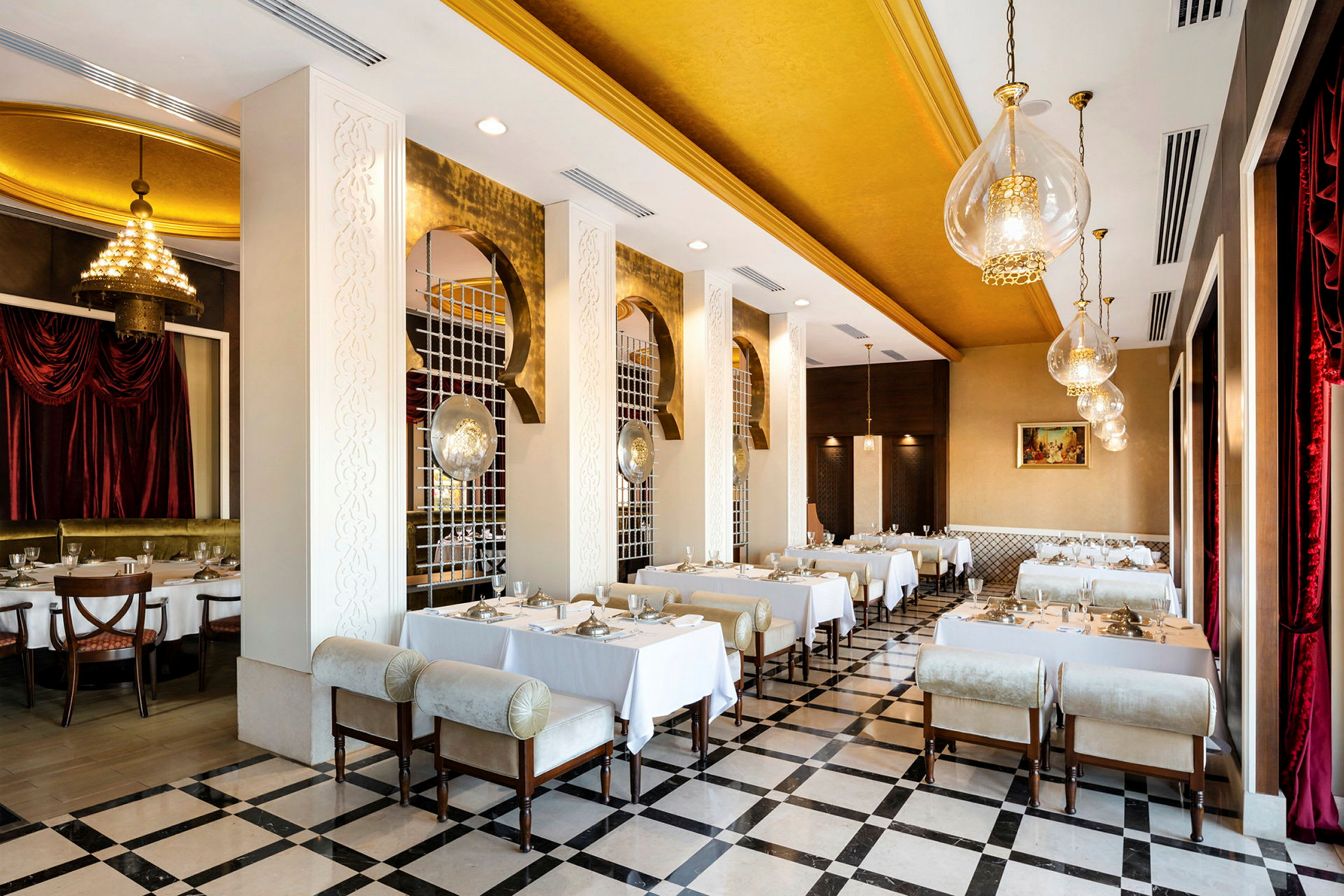 En elegant restaurant med gulddetaljer og hvide duge på bordene. (AI-genereret tekst)