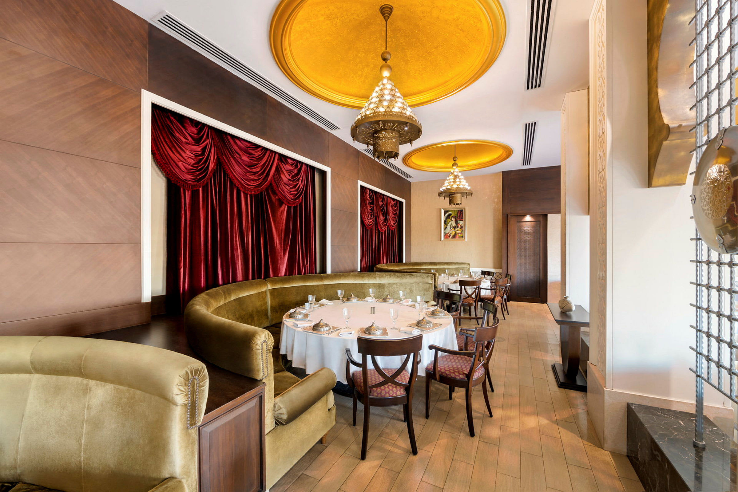 Interiør af en elegant restaurant med guldfarvede loftdetaljer og røde gardiner. (AI-genereret tekst)