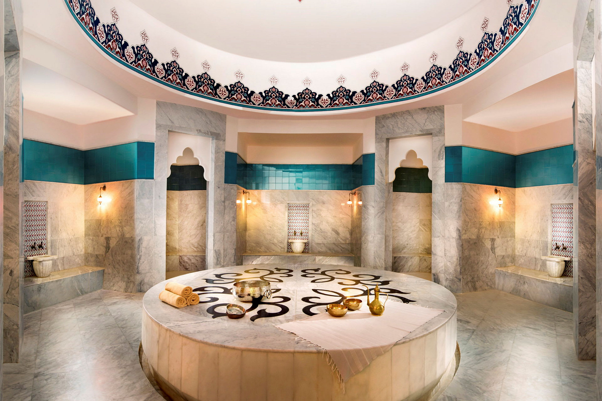 Et rum i en hamam med marmoroverflader, turkise detaljer og udsmykninger. (AI-genereret tekst)