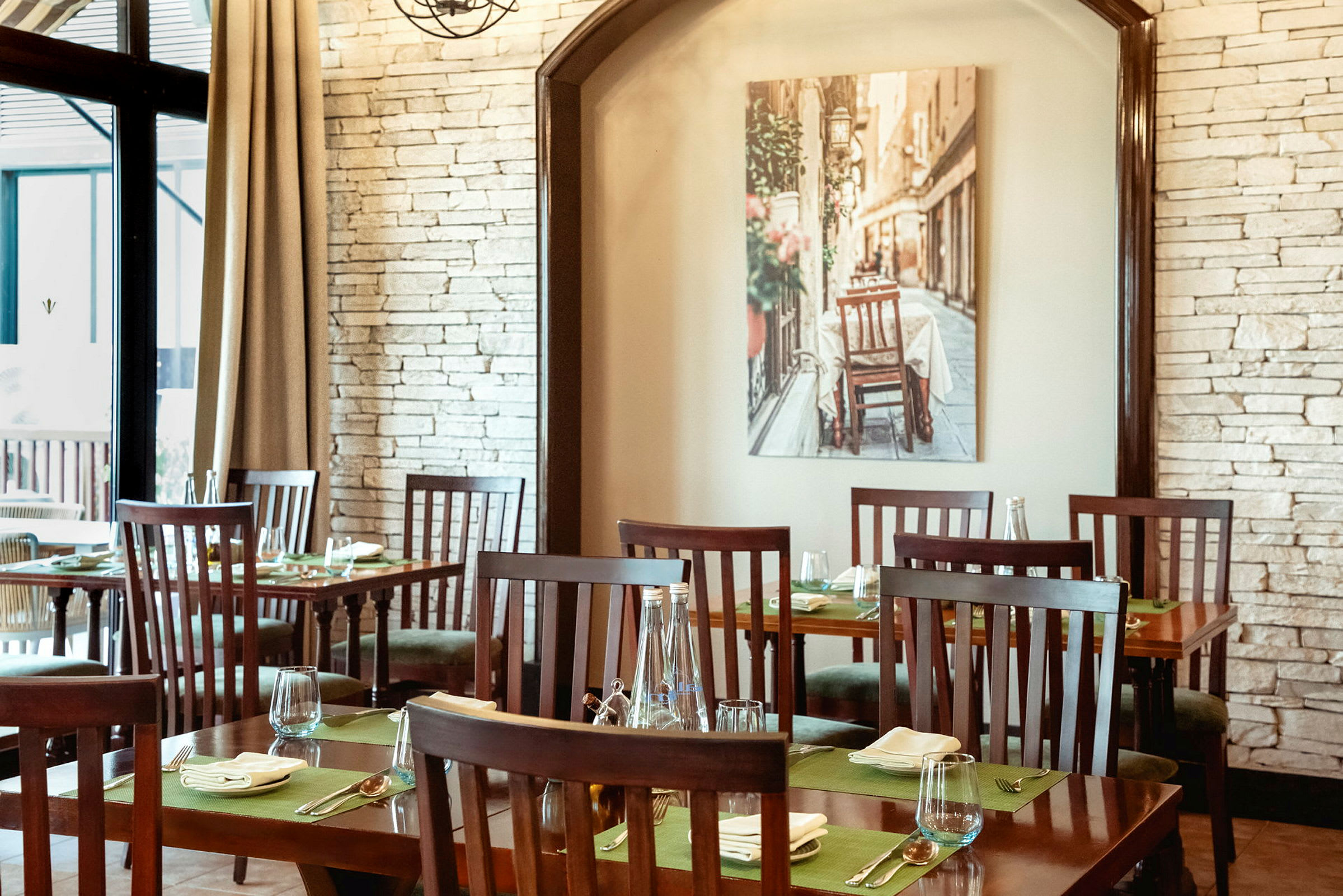 Interiør af en restaurant med træmøbler og dækkede borde, med et billede på væggen af en gade. (AI-genereret tekst)