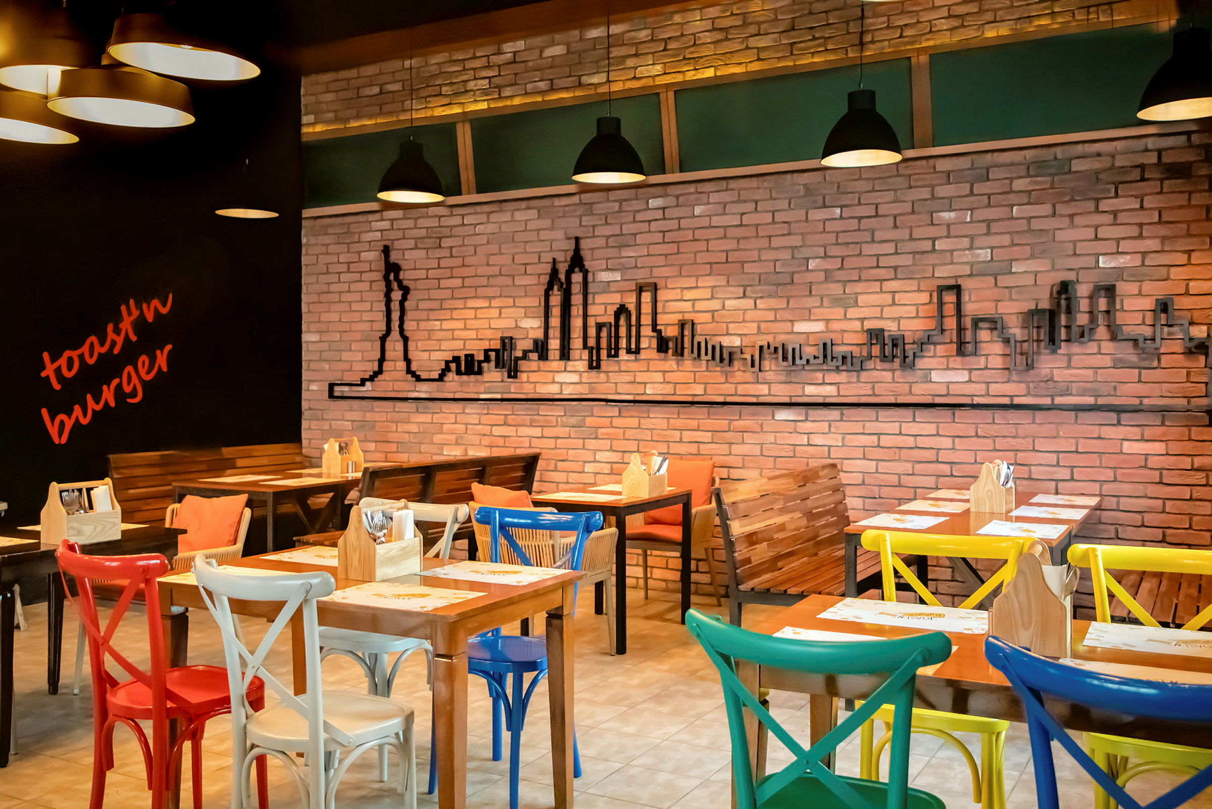 Tom restaurant med farverige stole, murstensvæg og New York-silhuet som dekoration. (AI-genereret tekst)