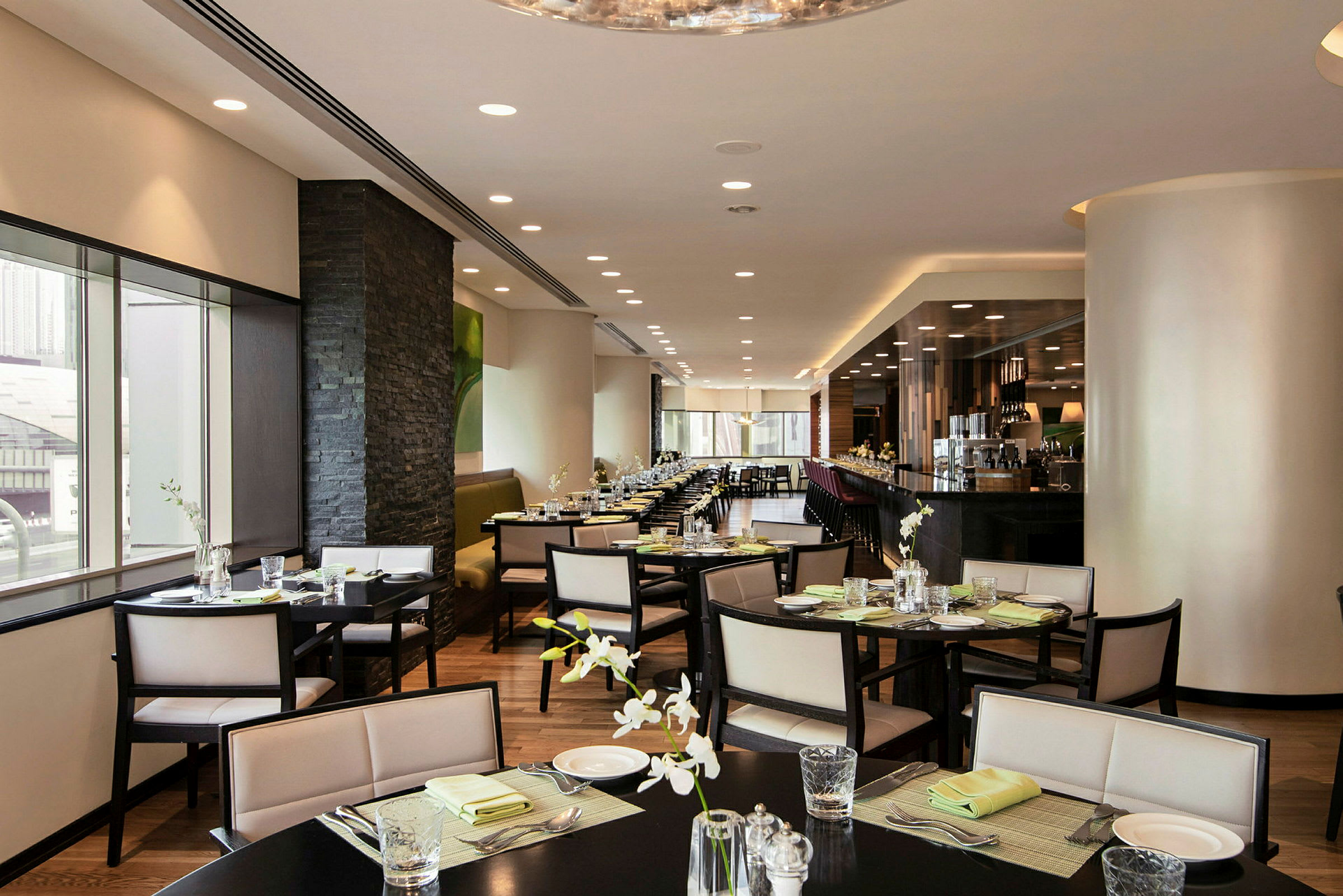 Restaurant med moderne indretning, elegante siddegrupper og lys borddækning. (AI-genereret tekst)