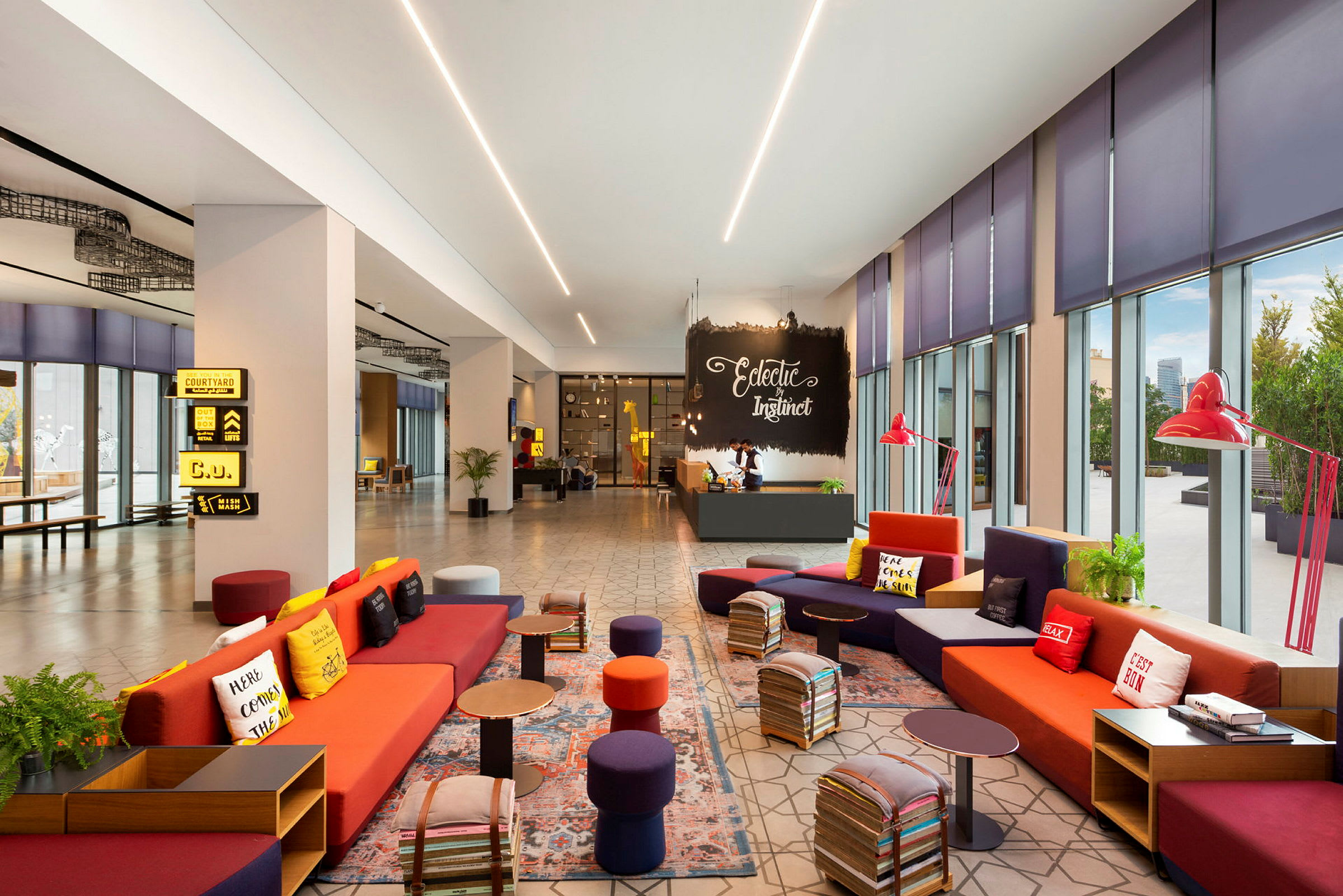 En moderne og farverig hotellobby med sofaer og små borde. Store vinduer giver naturligt lys. (AI-genereret tekst)