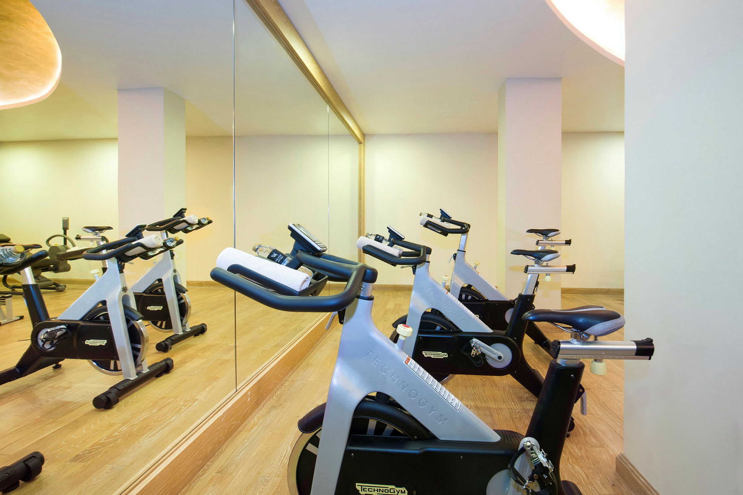 Billede af motionscykler i et fitnesscenter med spejlvæg. (AI-genereret tekst)