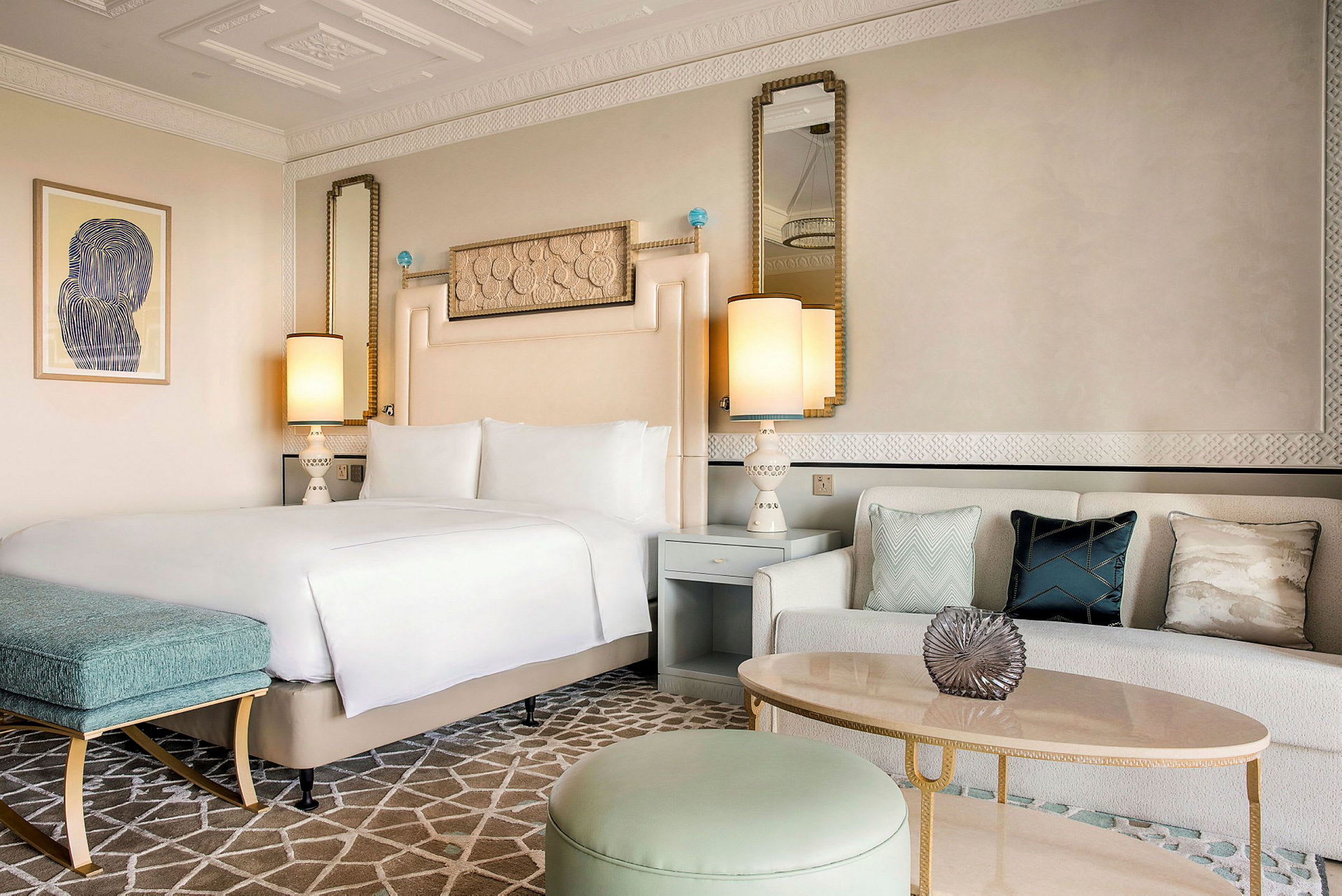 Et elegant hotelværelse med en dobbeltseng, en sofa med pyntepuder og et stilfuldt bord. (AI-genereret tekst)