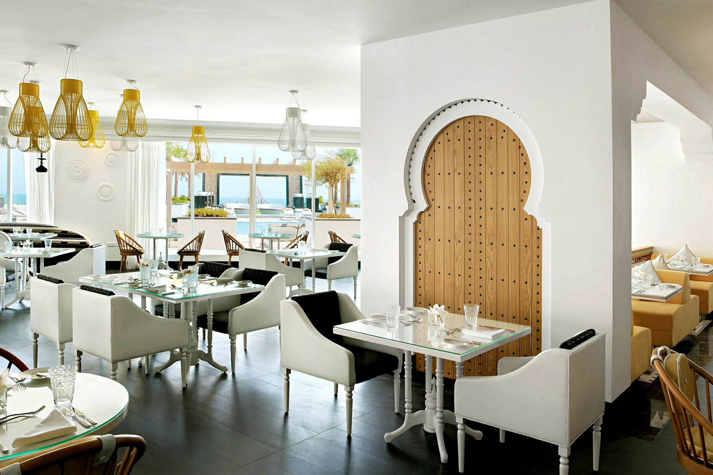 Interiør af en restaurant med moderne og stilfuldt design. Lyse siddepladser og belysning med en orientalsk træport. (AI-genereret tekst)