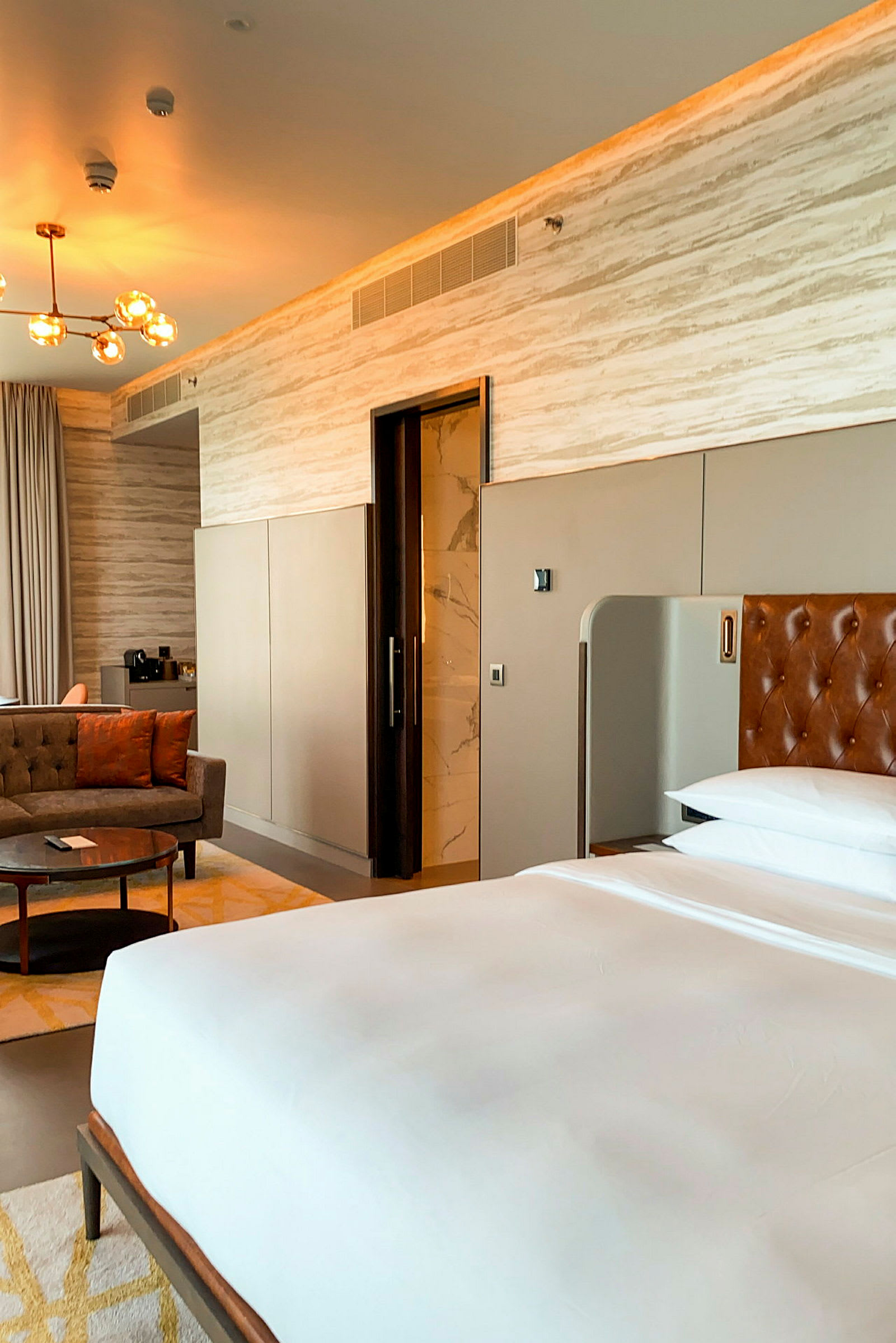 Et moderne hotelværelse med en seng, siddeområde og indgang til badeværelse. (AI-genereret tekst)