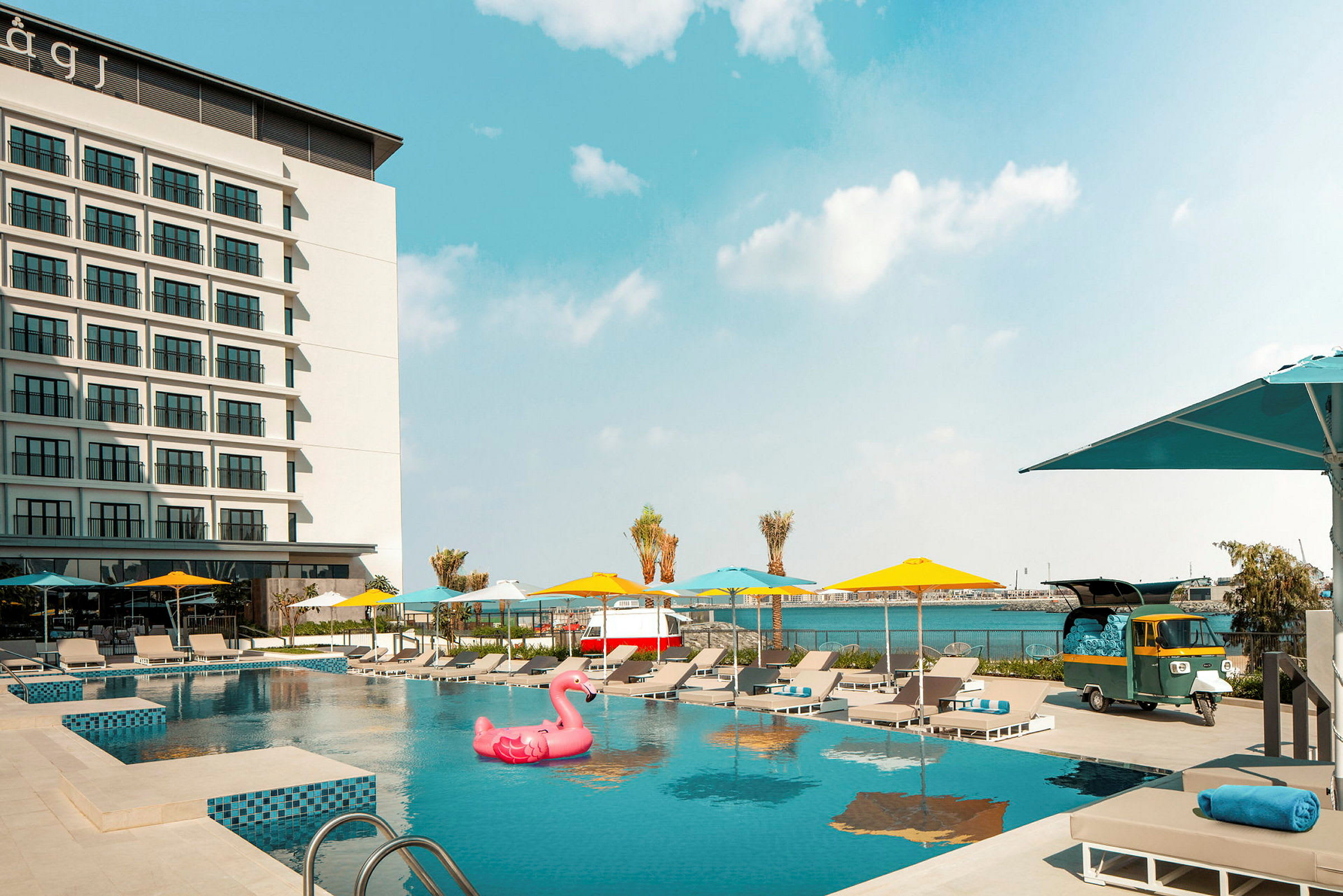 Hotelfacade med udendørs pool og liggestole. (AI-genereret tekst)